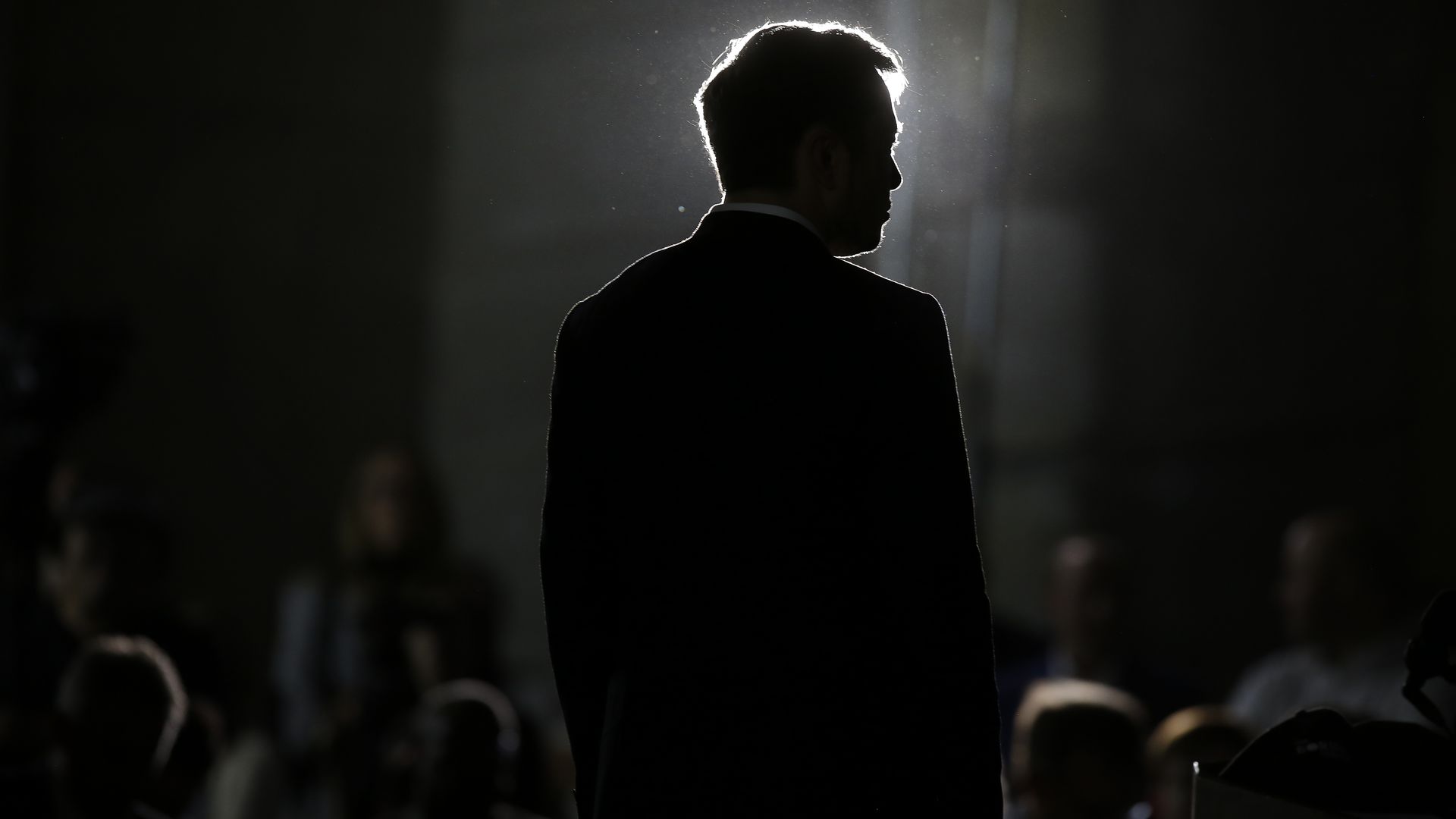 A dark image with the dark silhouette of Elon Musk