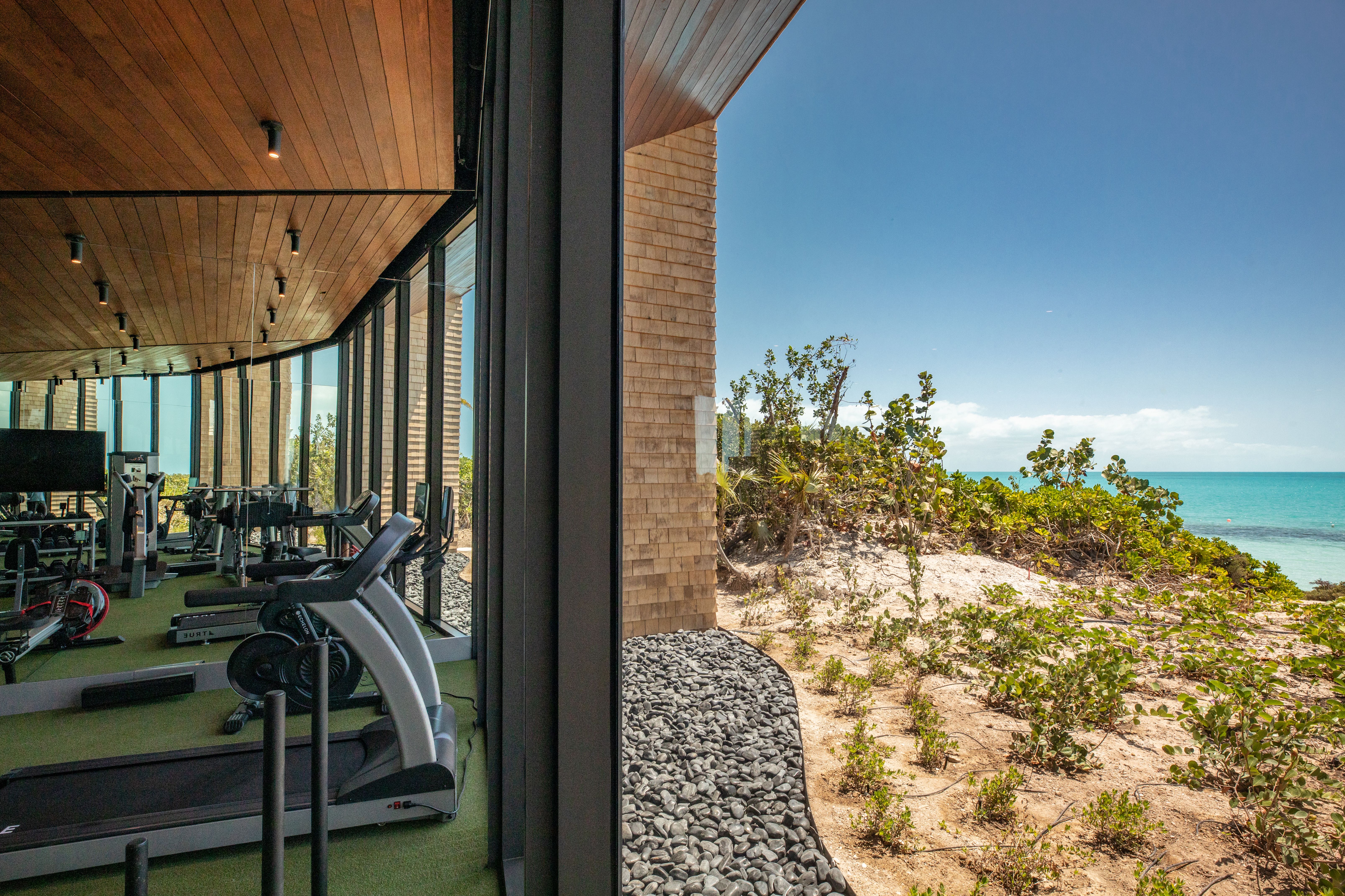An image depicting the interior of a gym and its tropical exterior, overlooking an ocean.
