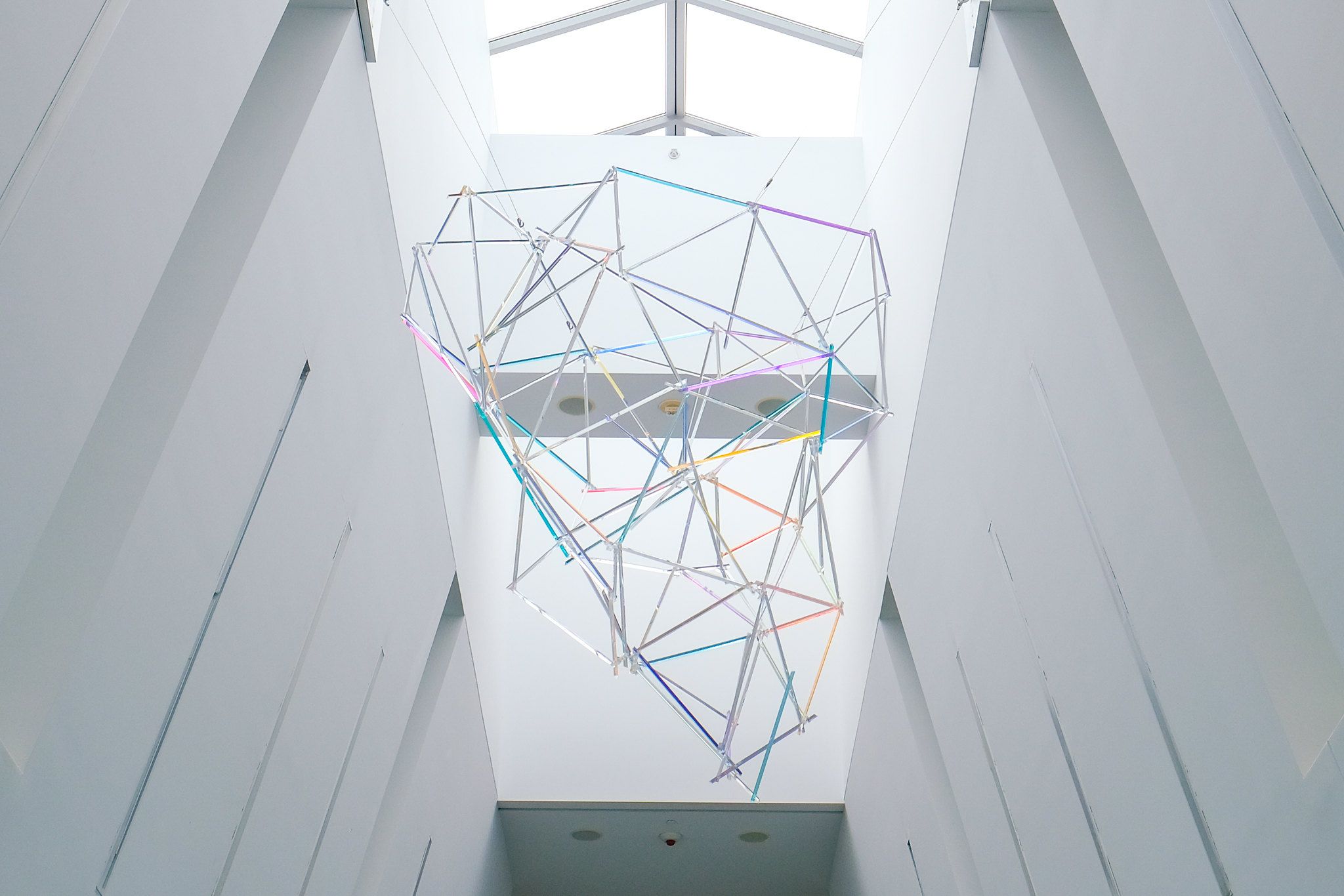 A hanging aerial sculpture made of colorful rods in an airport atrium. 