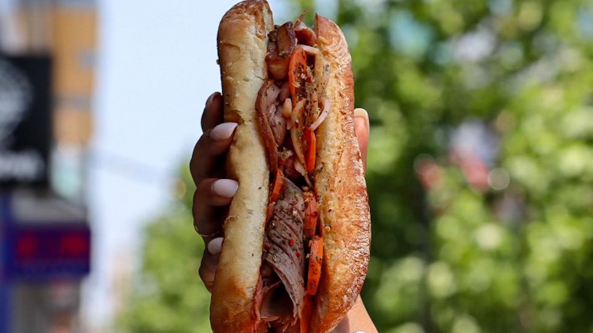 A hand holds a Chicago beef sandwich