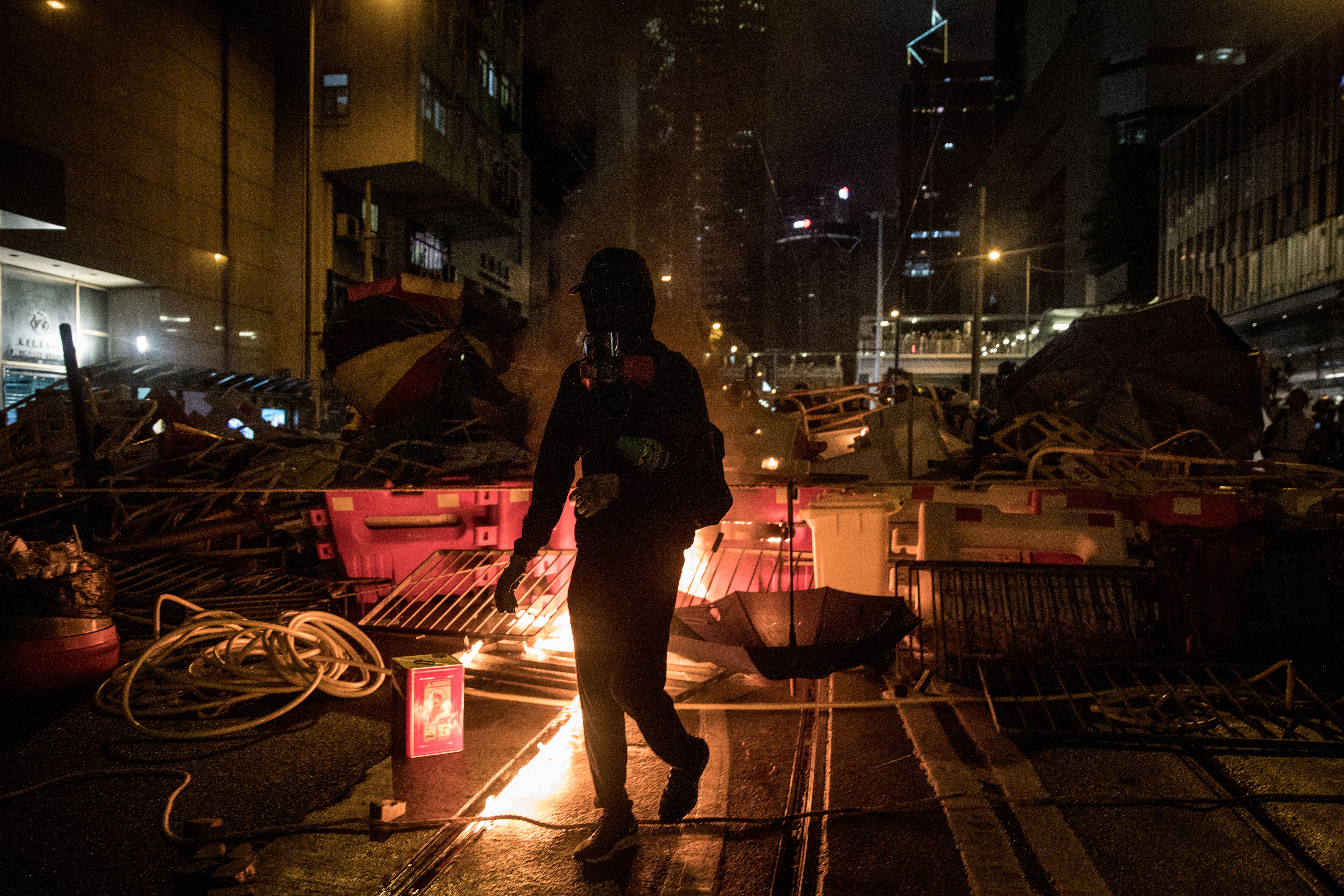 A Hong Kong protester walking in front of a burning barricade