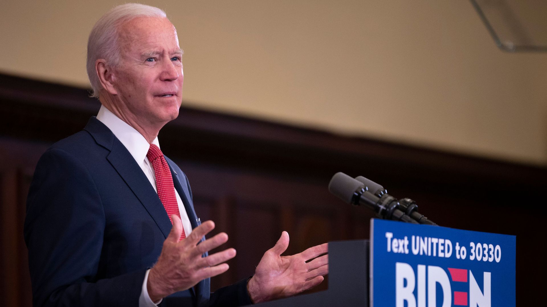 Former Vice President Joe Biden speaking at a podium with a 2020 campaign sign