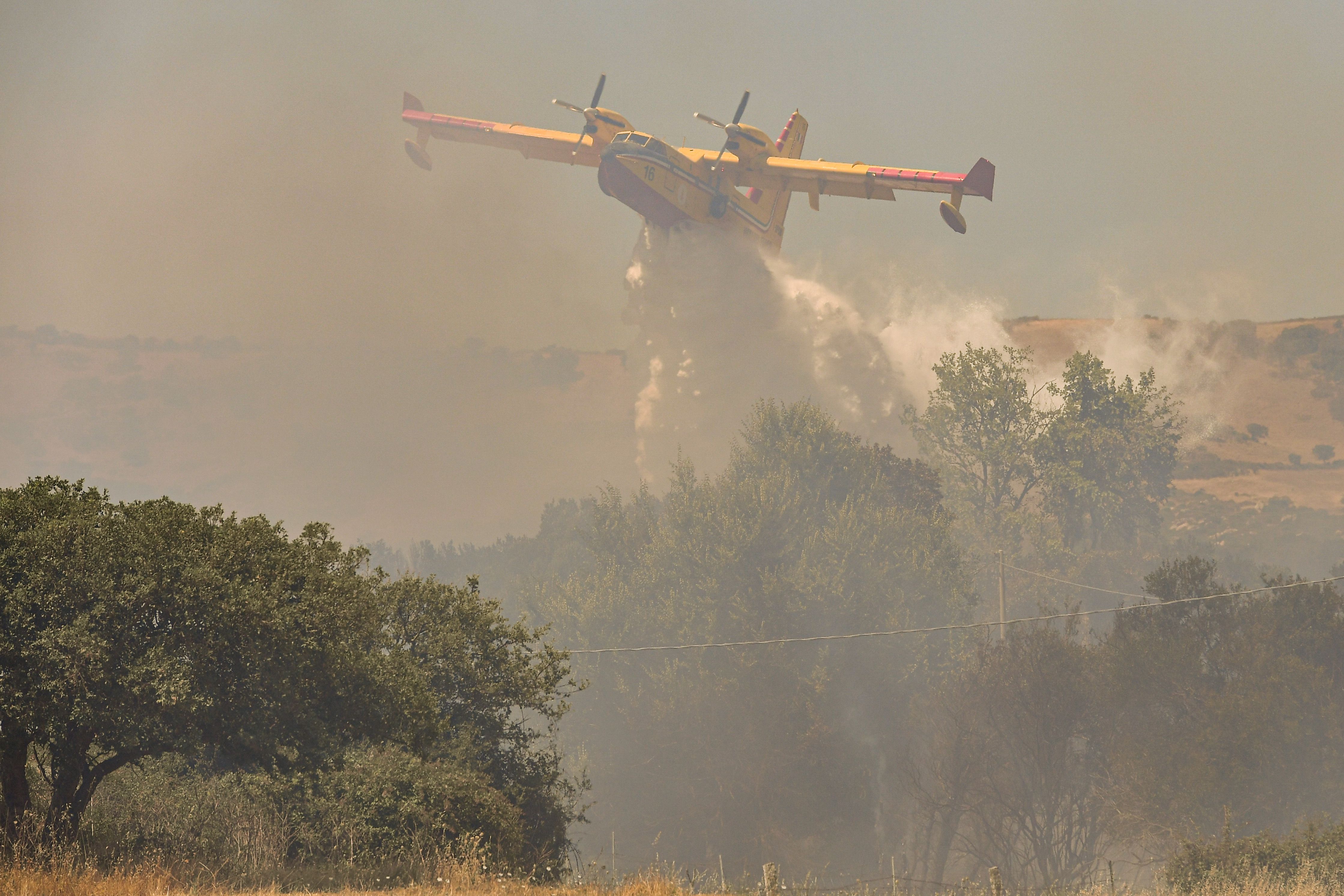 A tanker plane drops water on a fire that destroyed dozens of acres of land in Sassari province today on July 11, 2022 in Aggius, Sassari, Italy. 