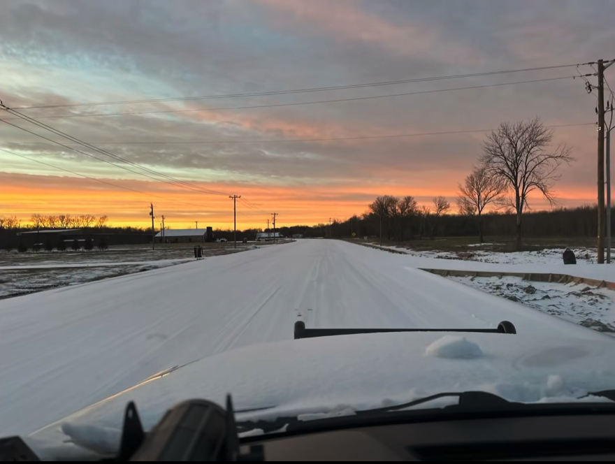 Photo shows a sunrise with snow on the road