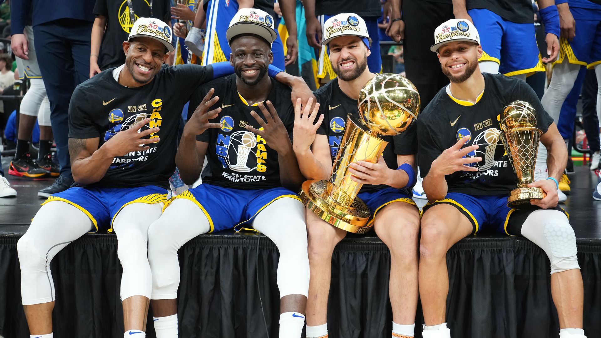 Four men smiling holding up four fingers