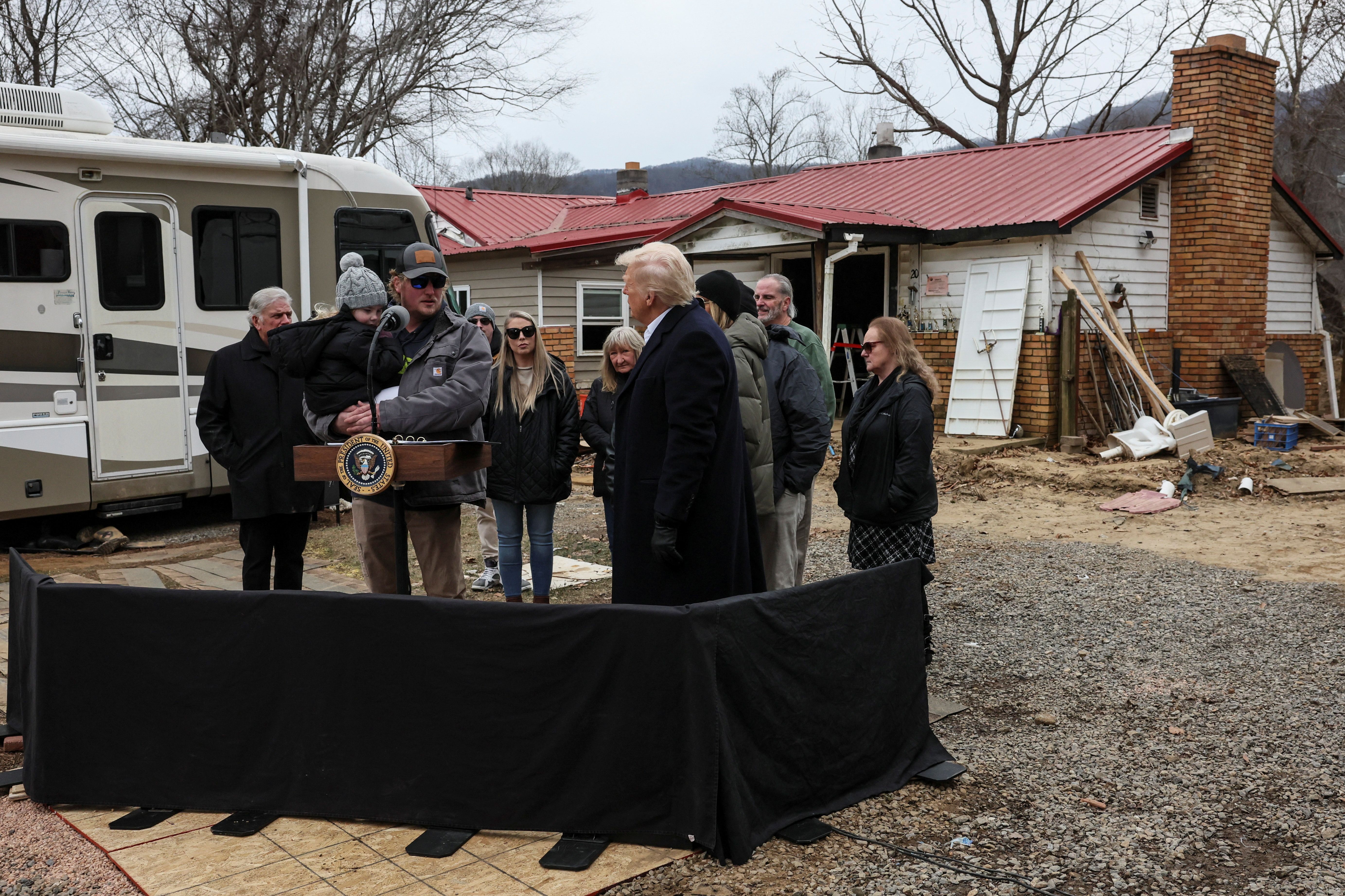 U.S. President Donald Trump and first lady Melania Trump listen to a man, carrying a child, affected by Hurricane Helene, as they tour areas devastated by the hurricane to assess recovery efforts in Swannanoa, North Carolina, U.S., January 24, 2025. REUTERS/Leah Millis TPX IMAGES OF THE DAY