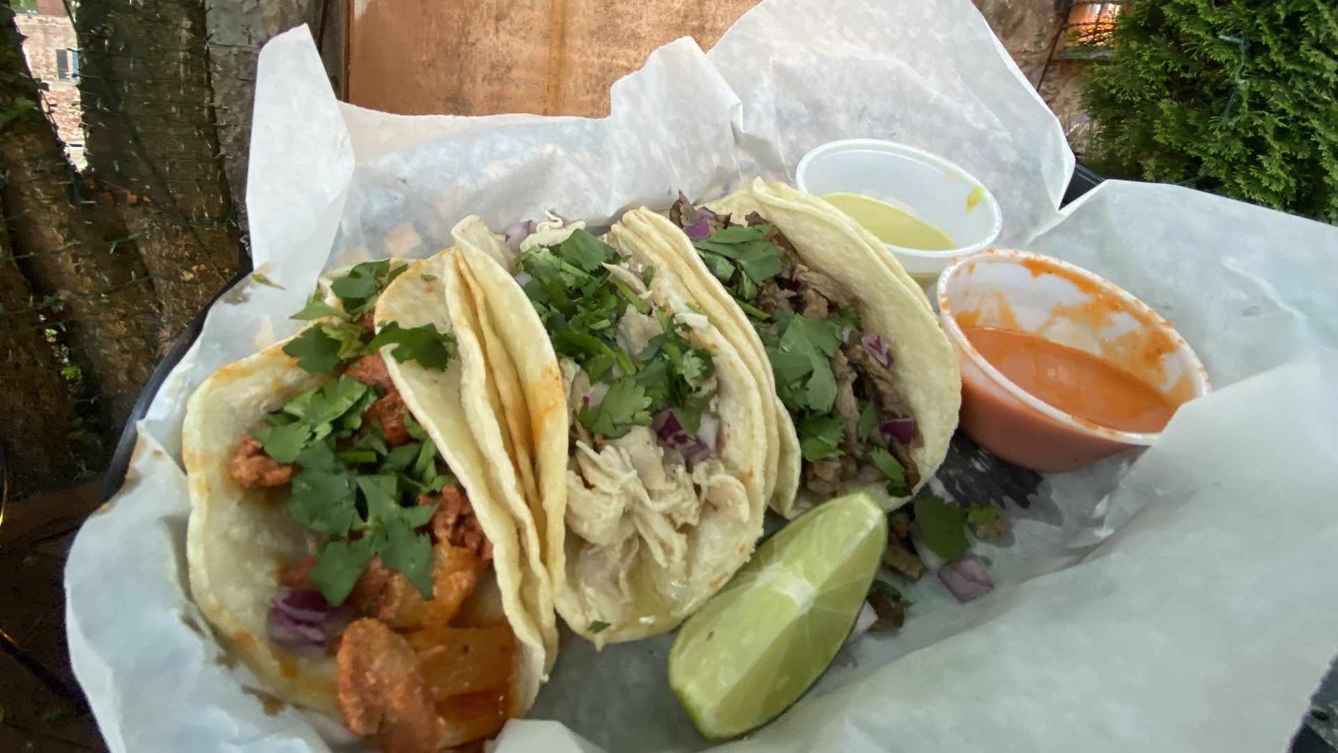 A trio of tacos in a paper basket. 