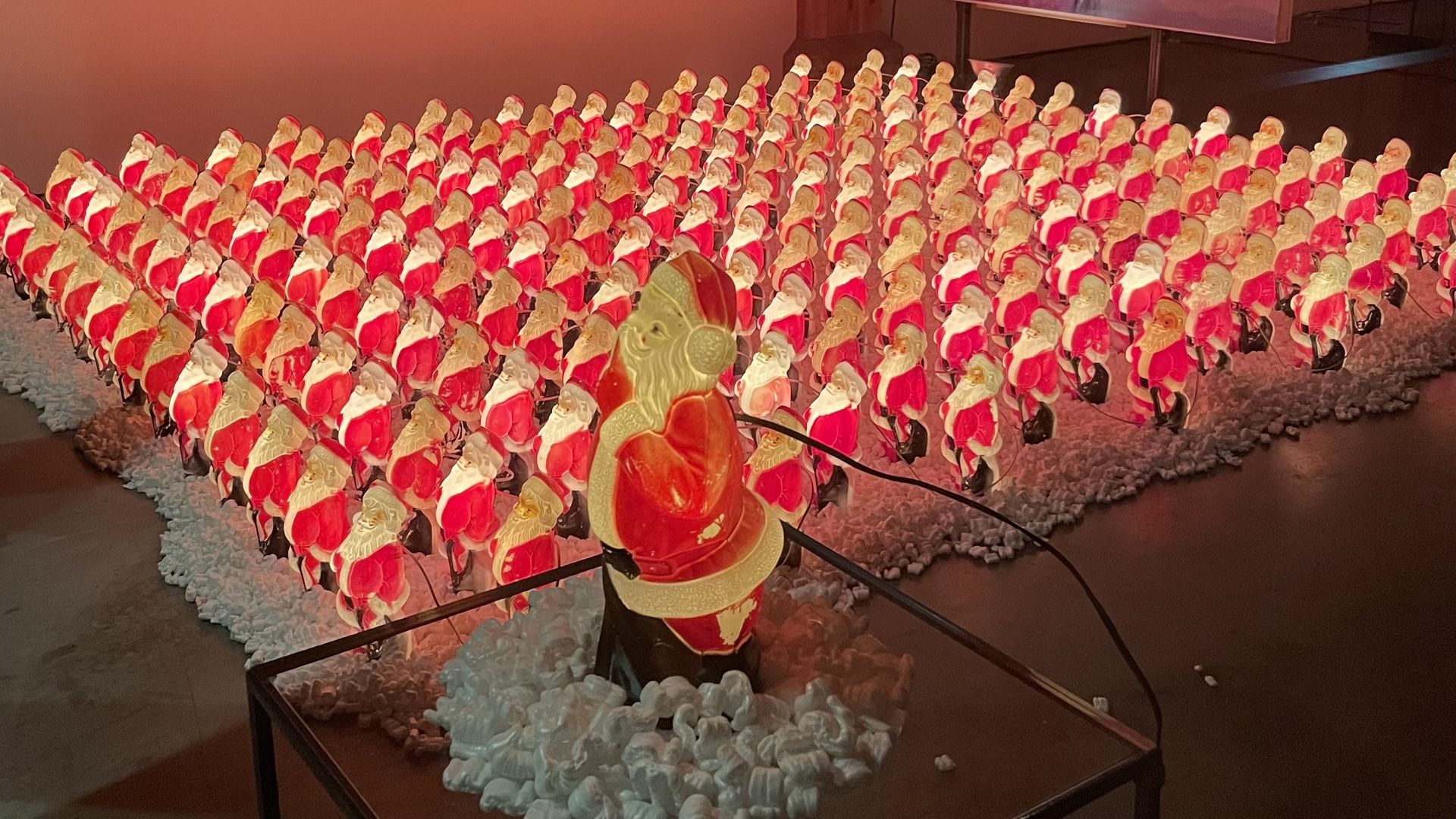 A photo of rows and rows of glowing Santa Claus statues.
