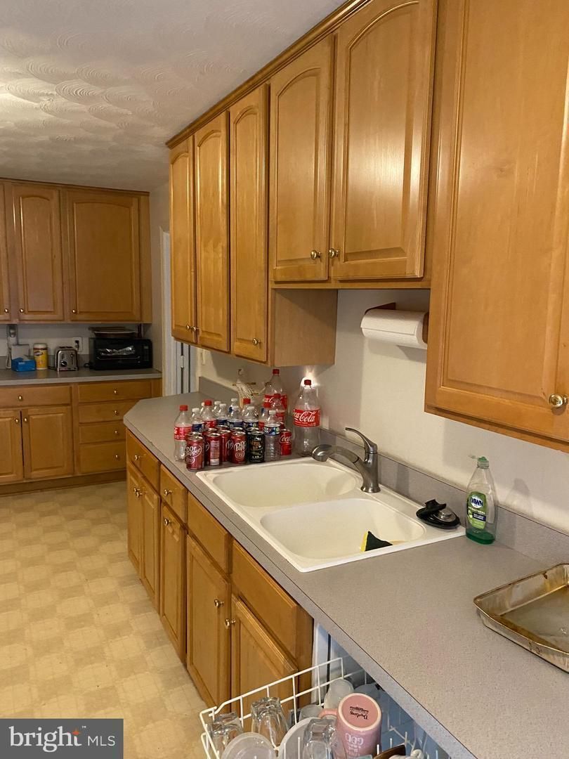 A kitchen with wood cabinets and bottles on the counter.