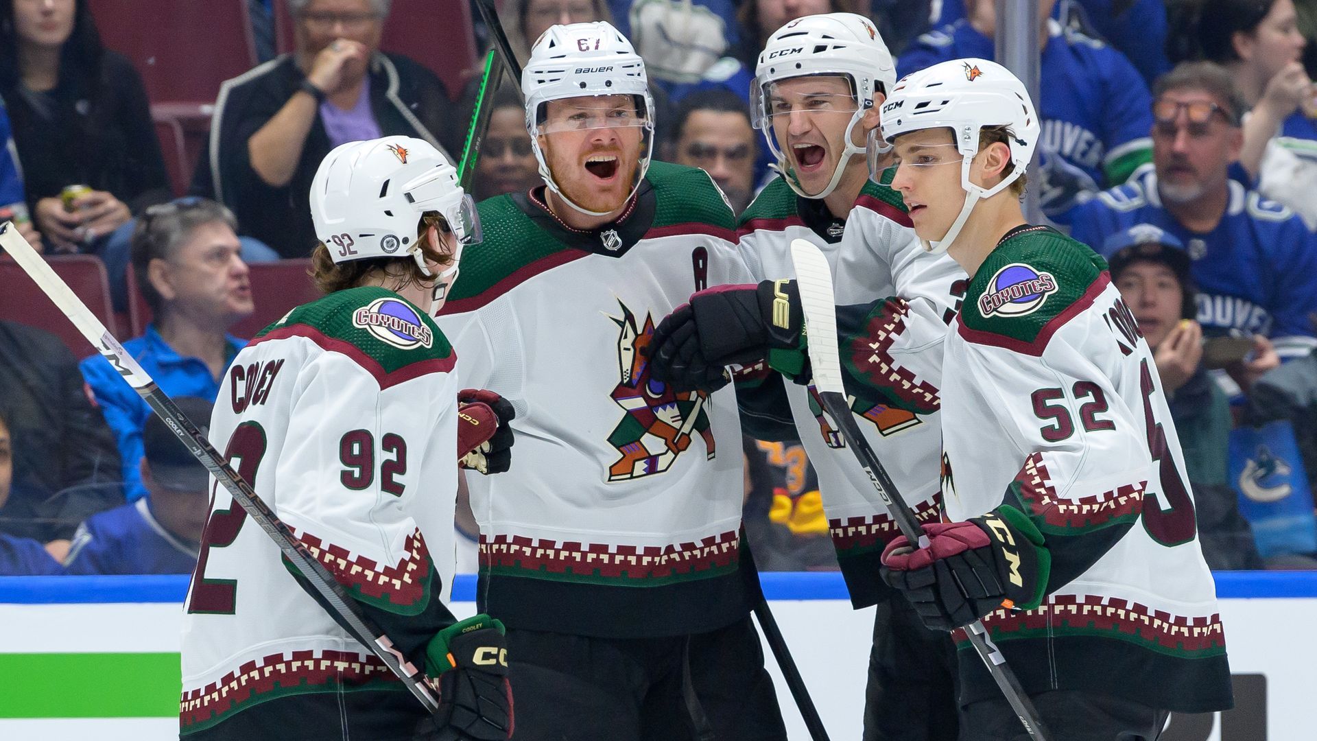 Arizona Coyotes hockey players celebrate in uniform on the rink.
