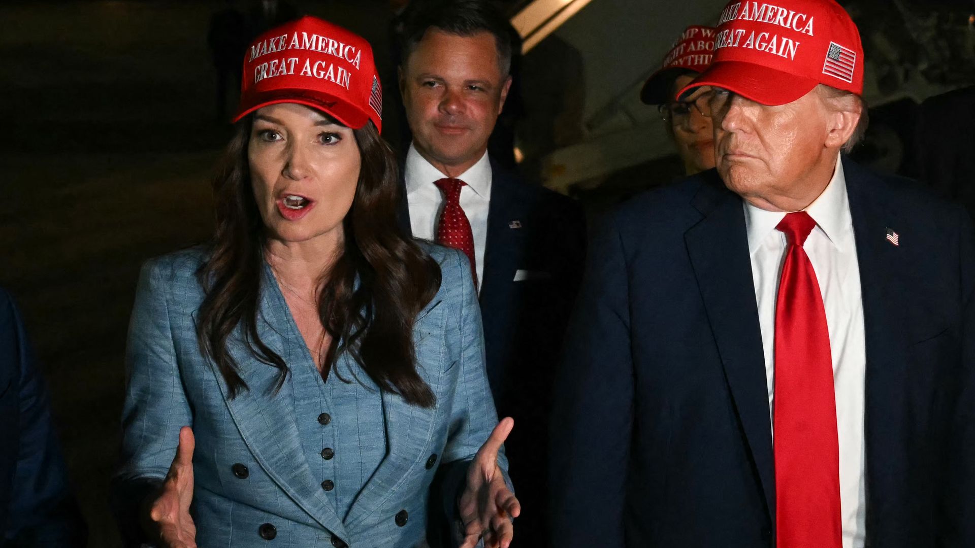  Secretary of Homeland Security Kristi Noem (R) and US President Donald Trump watch US Secretary of Agriculture Brooke Rollins (2L) talk to journalists as they arrive at Joint Base Andrews, Maryland early on July 4, 2025.