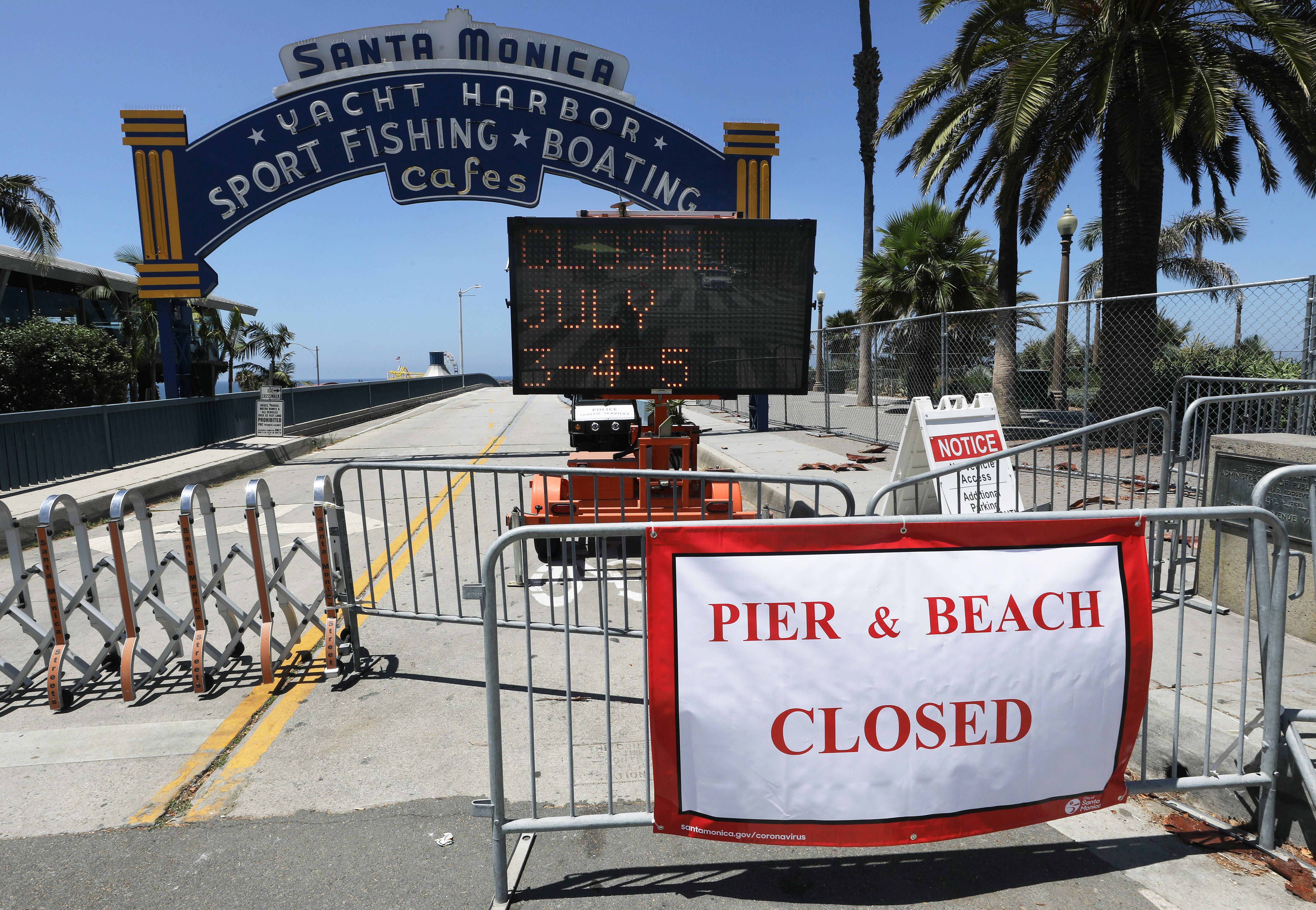 Signs are posted in front of the closed Santa Monica Pier saying the beach will be closed July 3-5