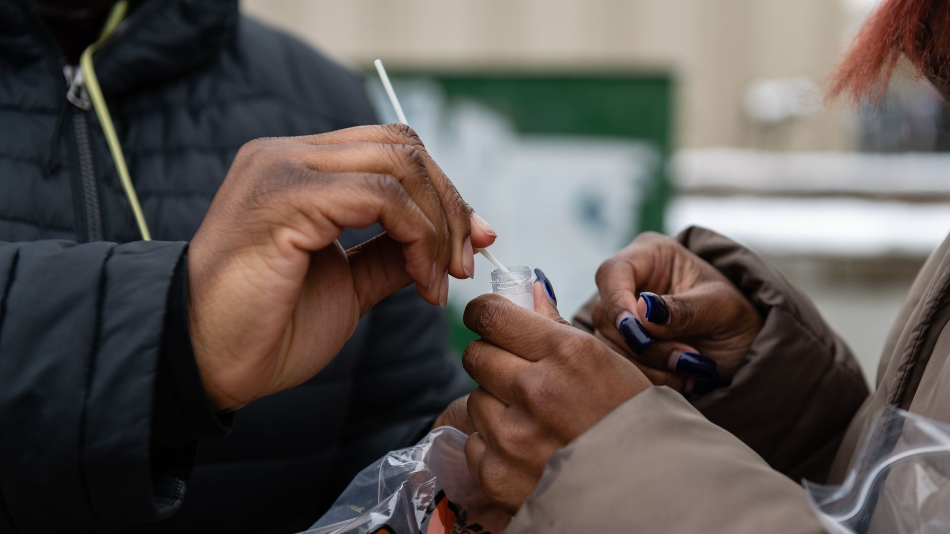 Someone puts a COVID-19 swab into a vial