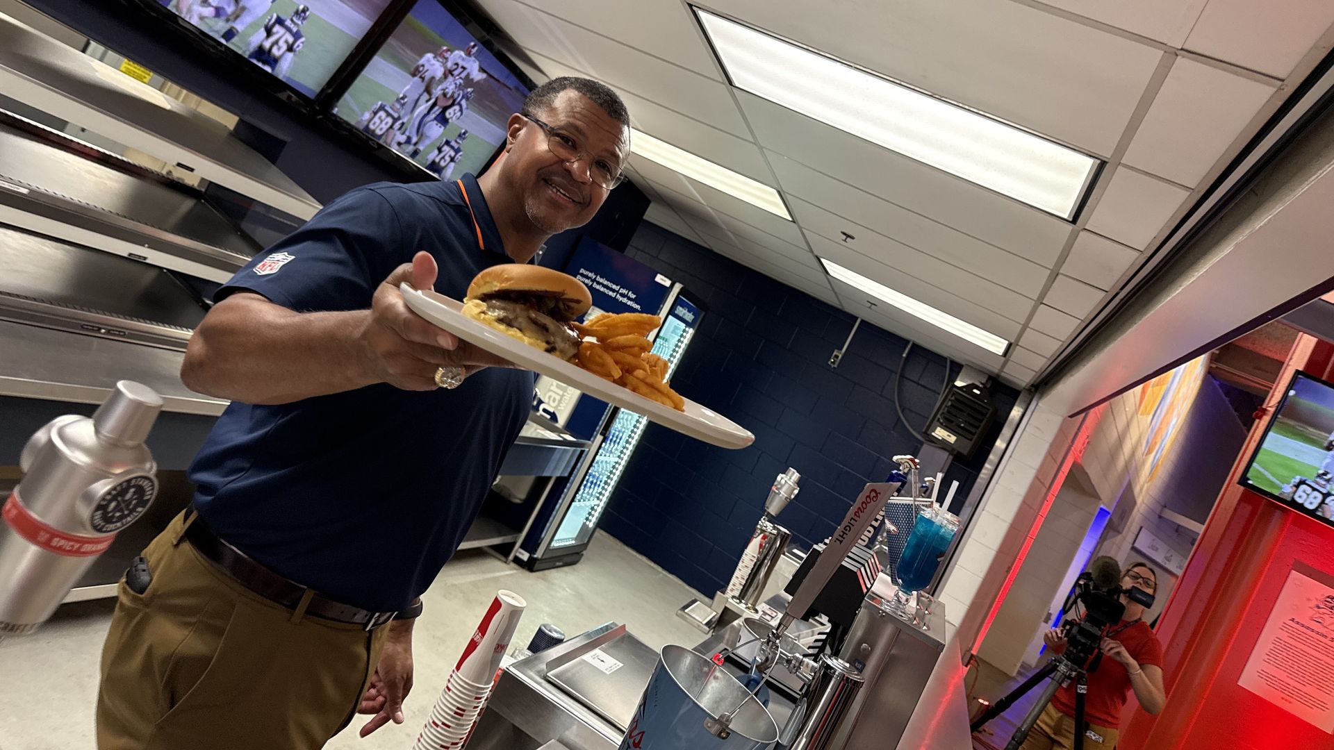A man holds up a burger with fries to show its details. 