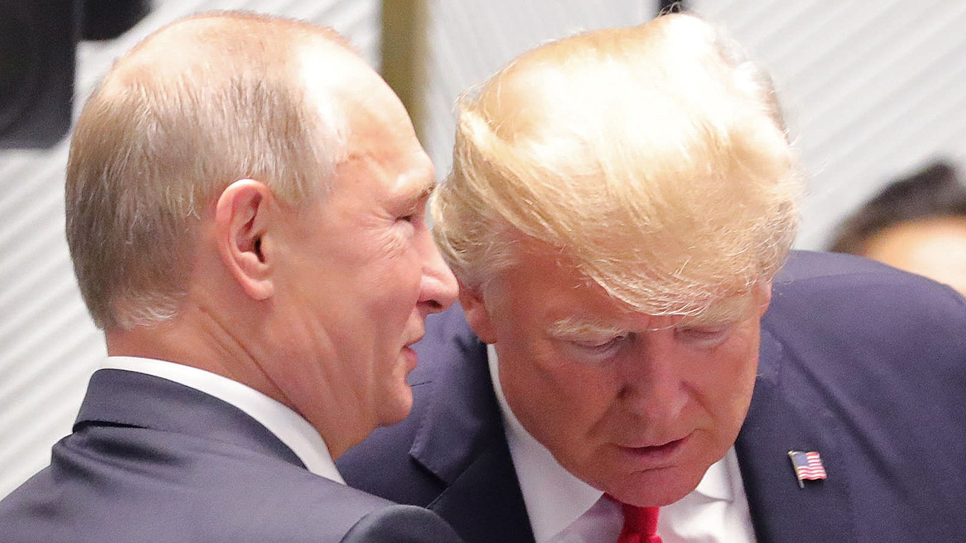 Vladimir Putin whispering to Donald Trump during a meeting of world leaders.