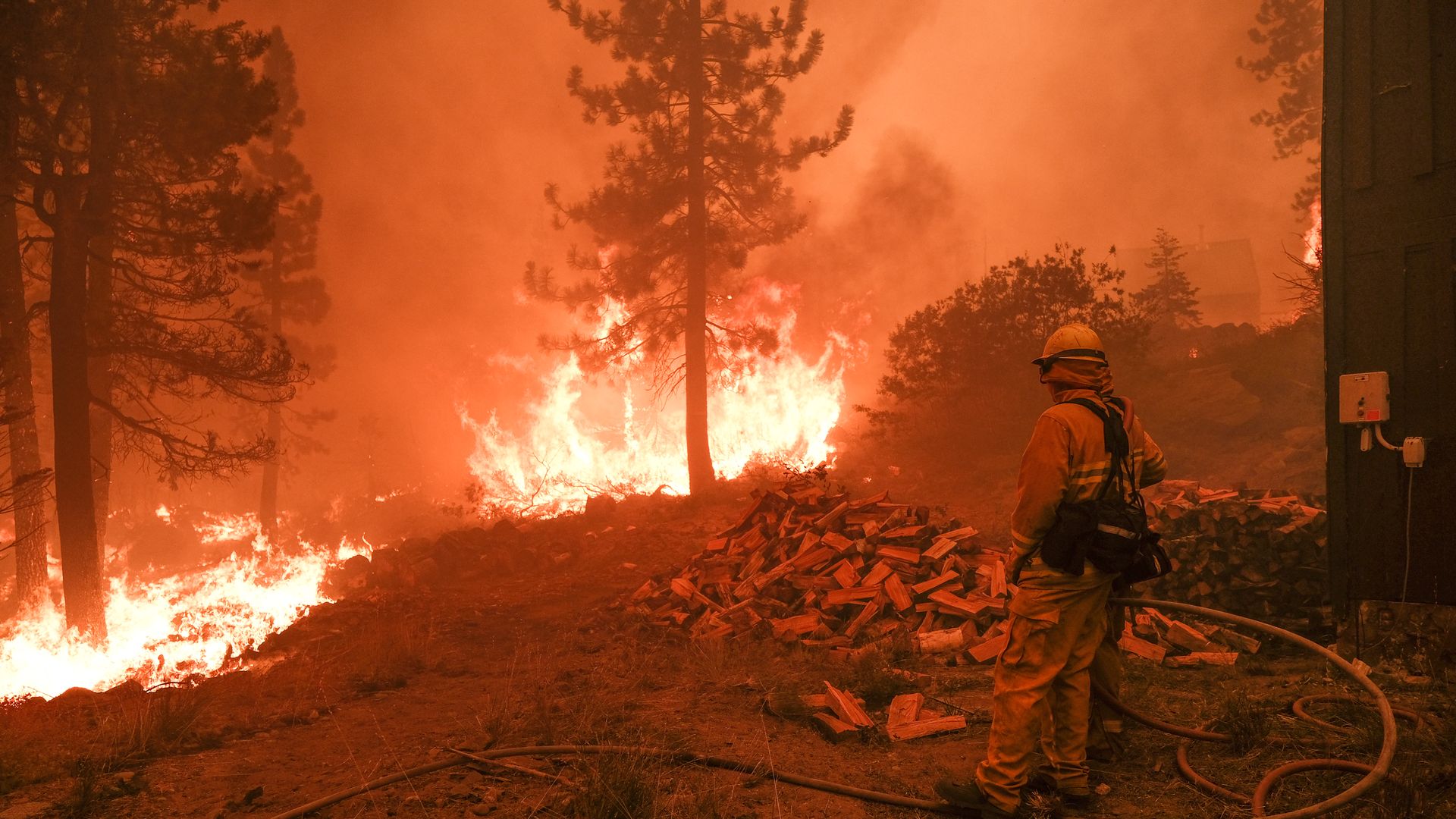 A firefighter monitors a fire threatening the Echo Summit Lodge during the Caldor Fire on Aug. 30.