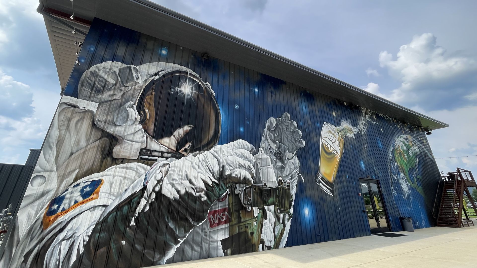 A mural on the side of Back Forty Beer Company's Huntsville taproom shows an astronaut floating in space and reaching for a pint of beer also floating in space.