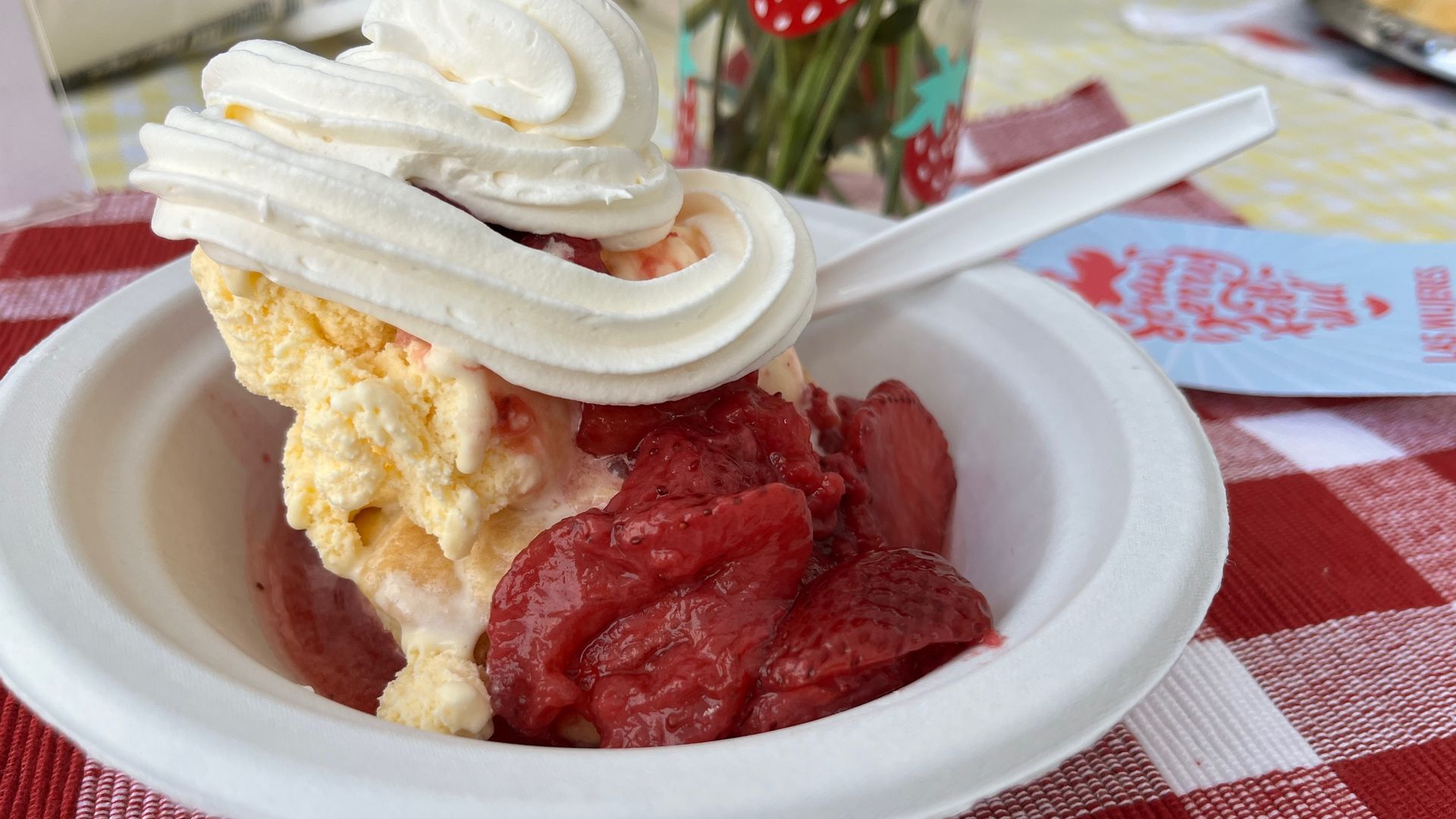 Whipped topping on top of ice cream and shortcake with strawberries in syrup. 