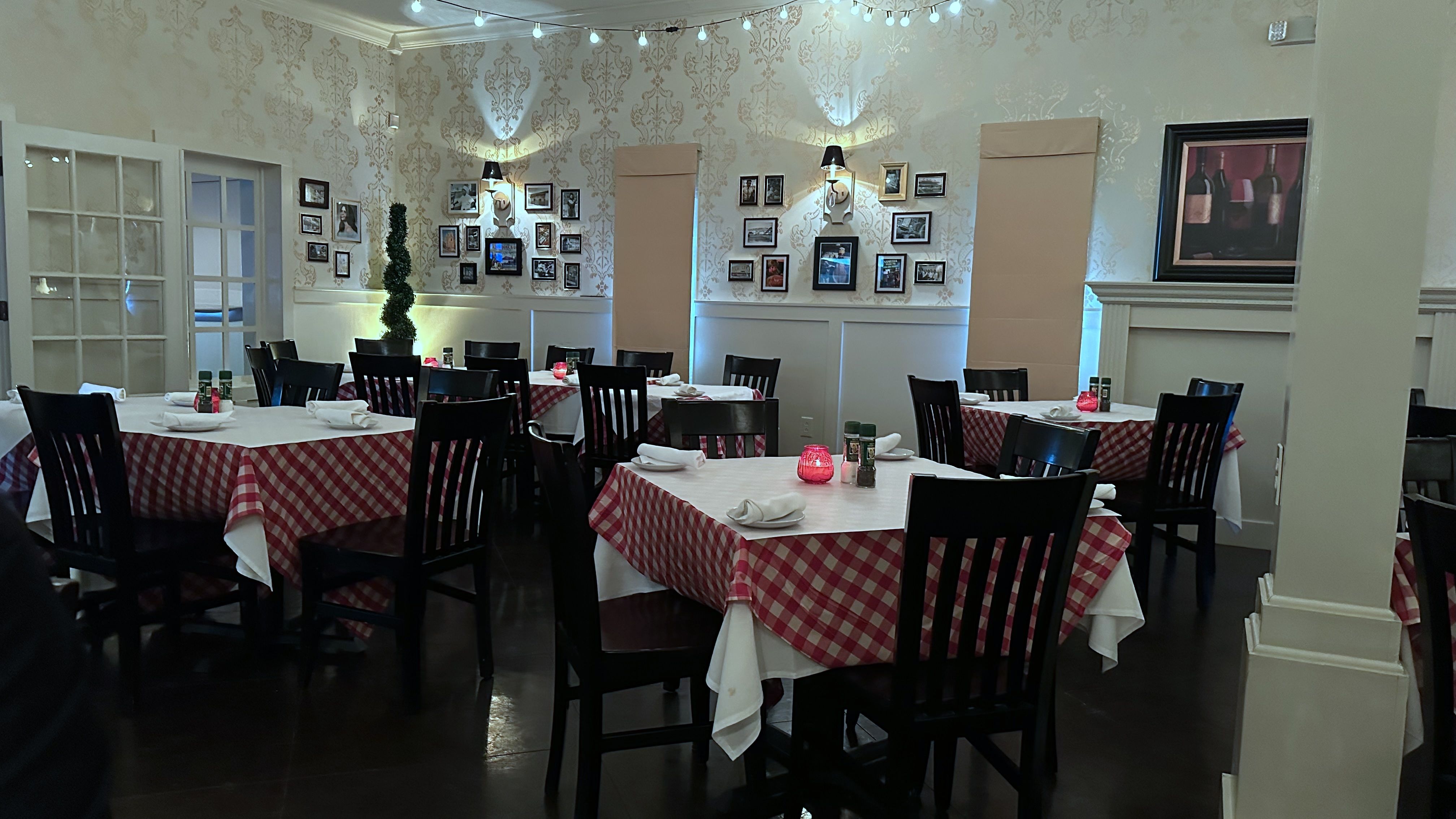 An empty dining room with paper-topped red-and-white checked tablecloths.