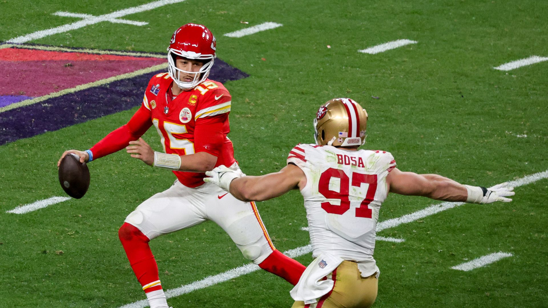 Quarterback Patrick Mahomes #15 of the Kansas City Chiefs looks to throw under pressure from defensive end Nick Bosa #97 of the San Francisco 49ers in the fourth quarter of Super Bowl LVIII