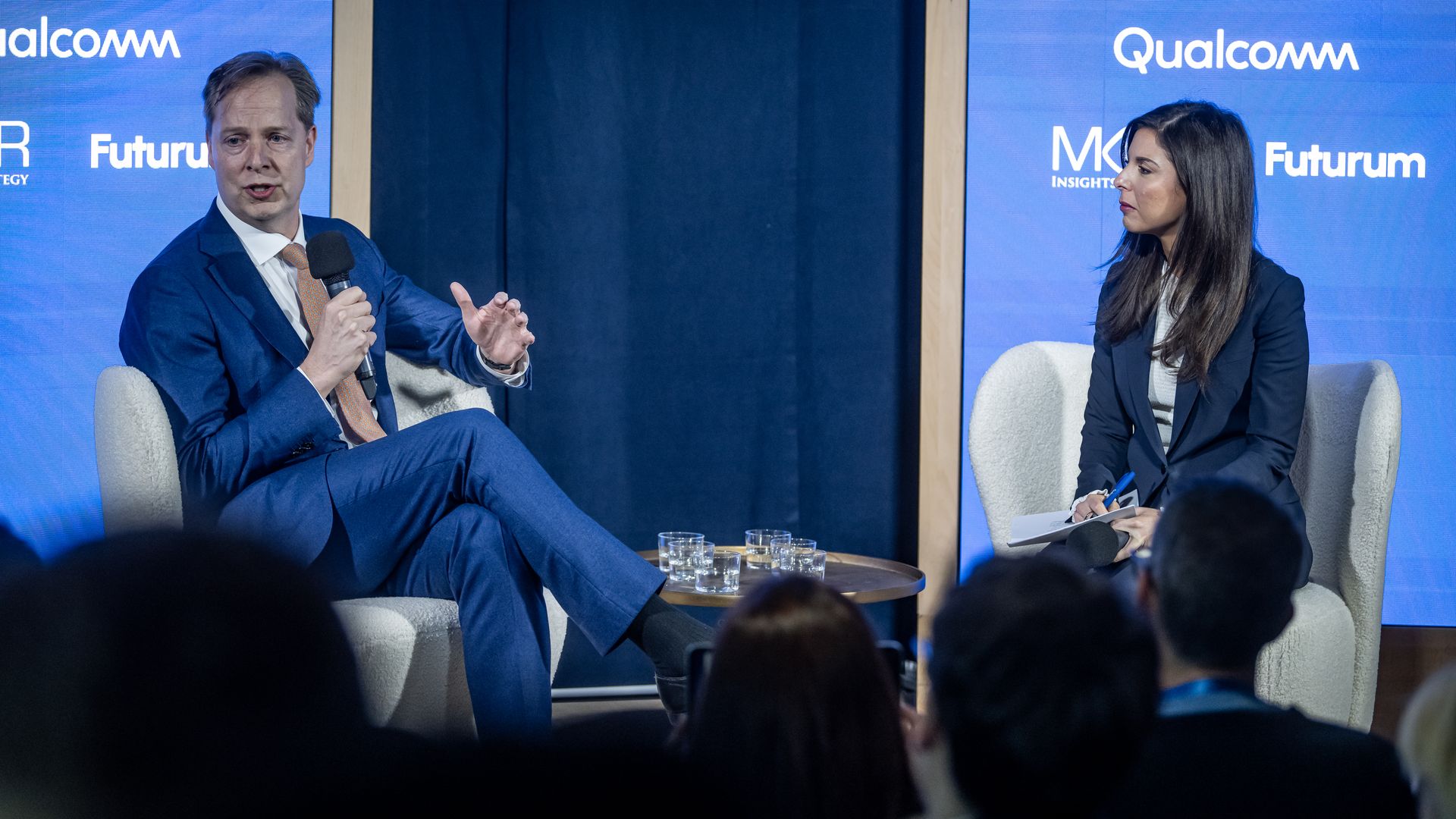 Dow Jones CEO Almar Latour and Axios' Sara Fischer sitting on chairs on a stage with the words Qualcomm and Futurum on screens in the background