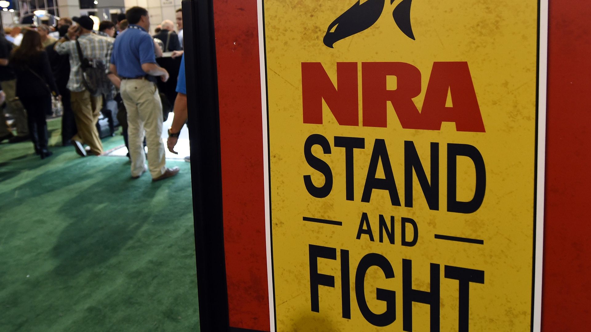  Convention attendees pass by a sign for the National Rifle Association at the 2016 National Shooting Sports Foundation's event