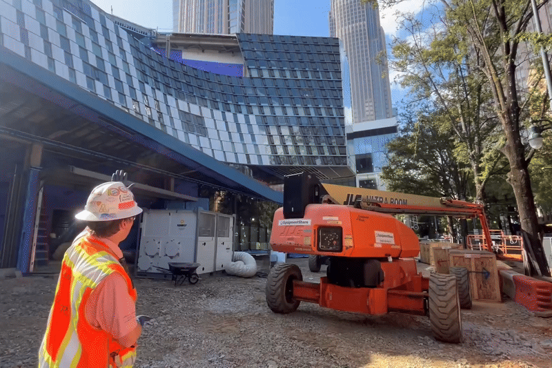 Person in construction hat points to job site