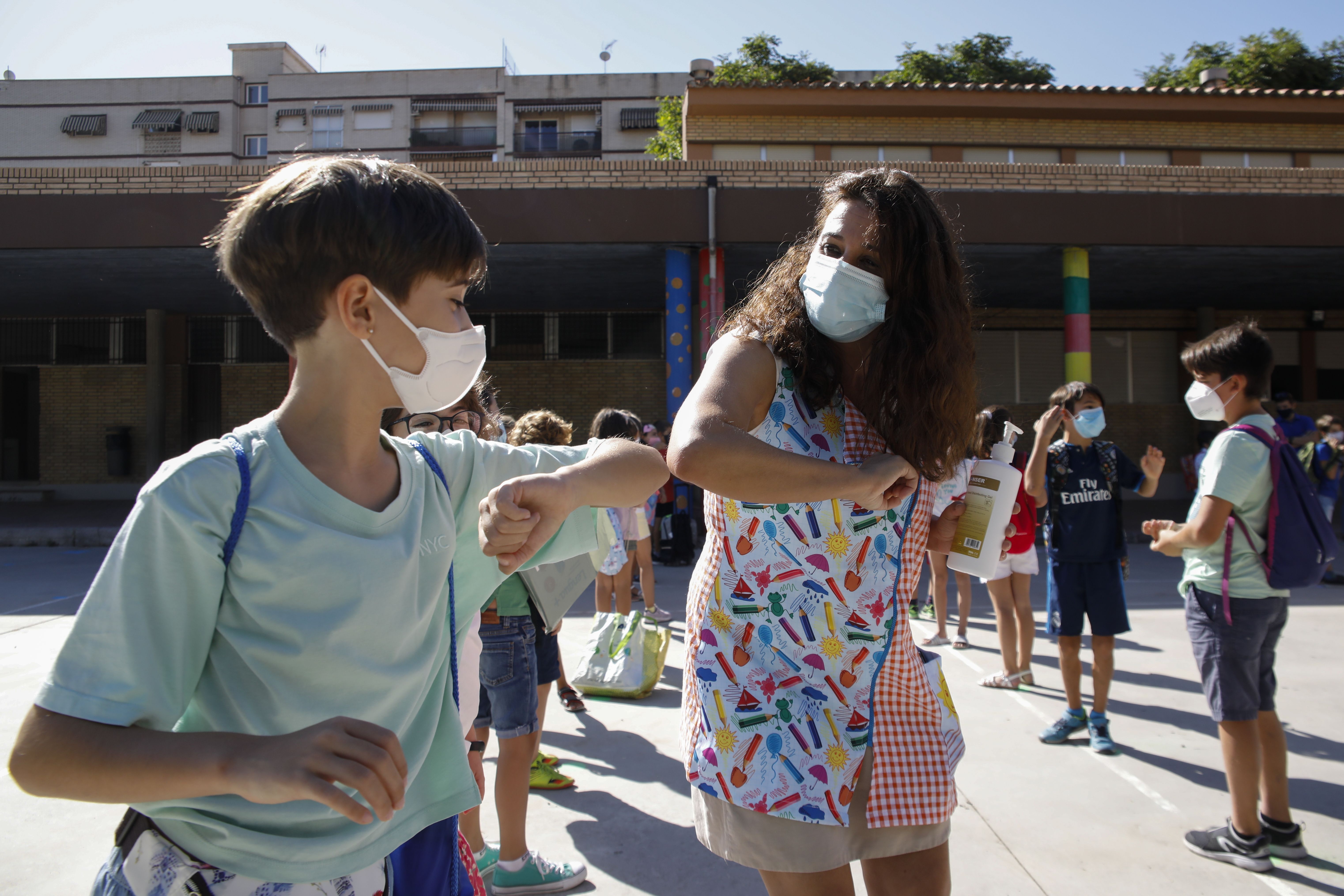  A teacher and a student bumping elbows before entering to class during the first day of school on September 10, 2020 in Granada, Spain. 