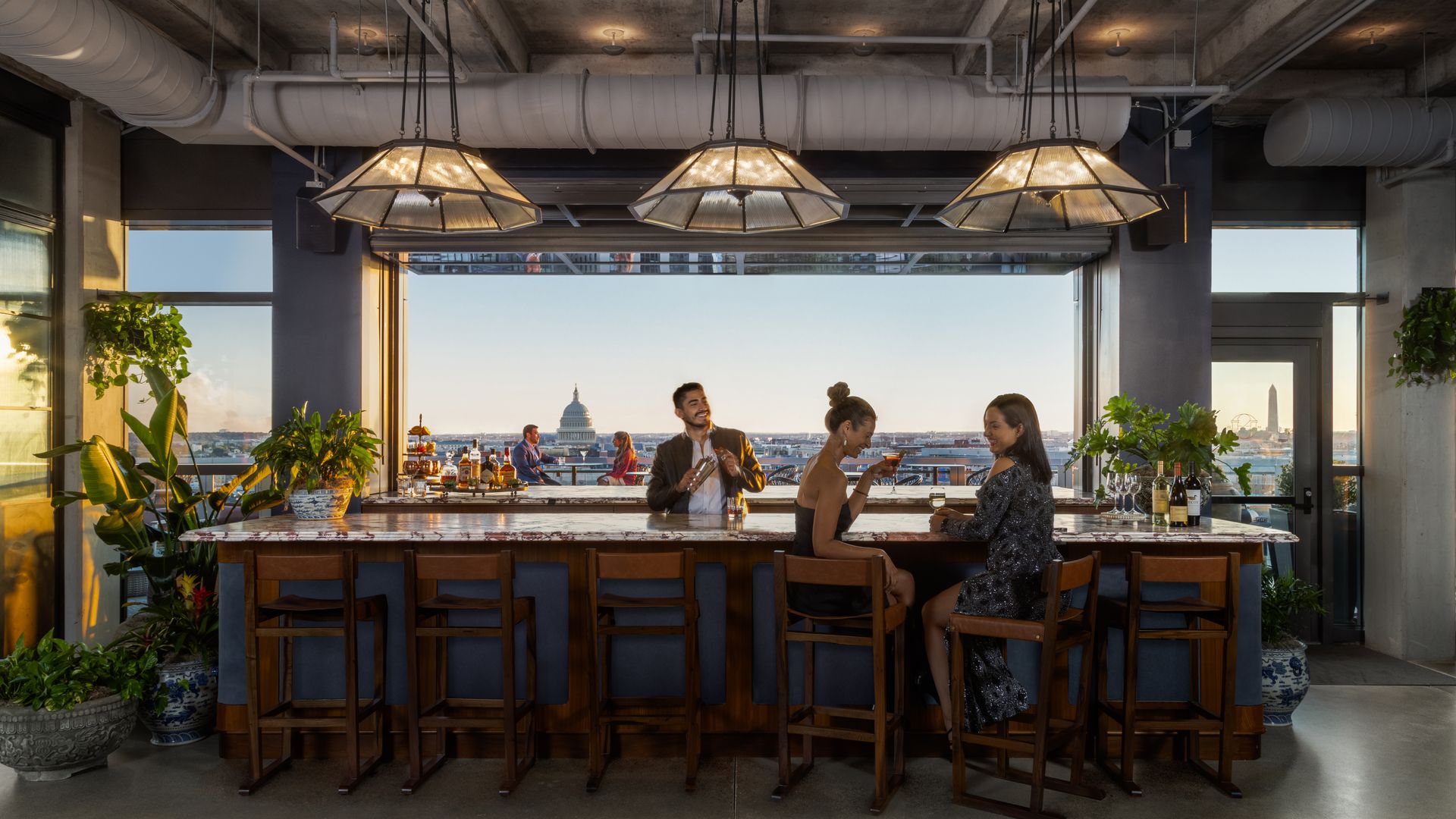 A top floor penthouse overlooking the Capitol Building with a bar where two ladies sit having drinks