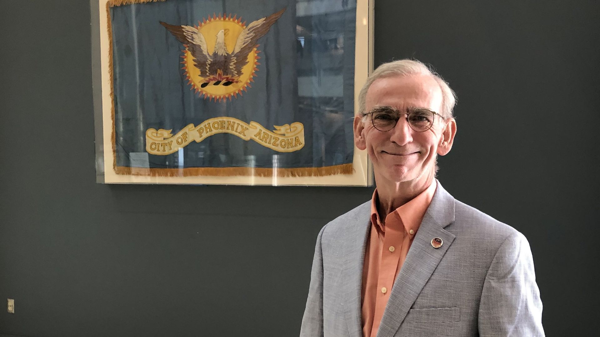 A man stands in front of a flag.