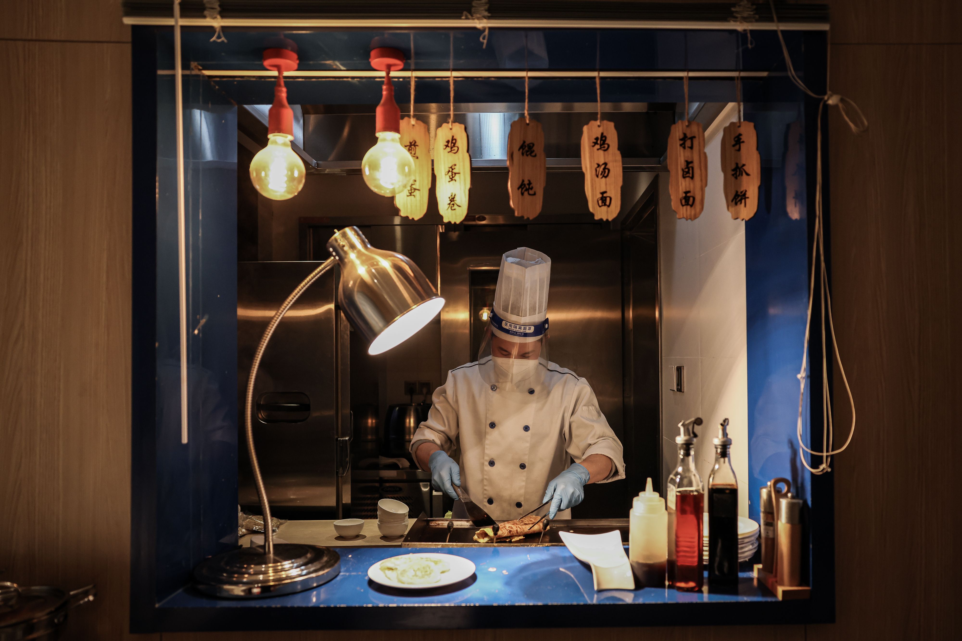 A chef wears a protective face mask with a shield as he prepares breakfast at a hotel in the closed loop on February 04, 2022 in Beijing, China.