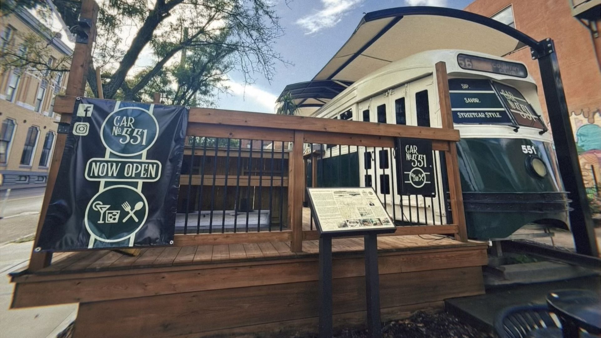 Outdoor view of Car No. 551, a vintage green and white streetcar converted into a dining spot with a black sign saying \