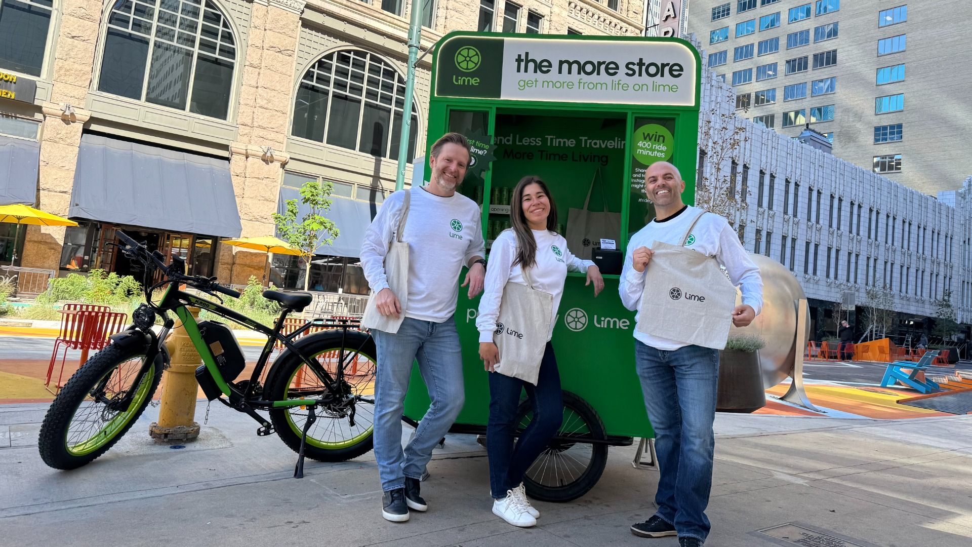 People pose in front of a bike-powered green Lime cart. 