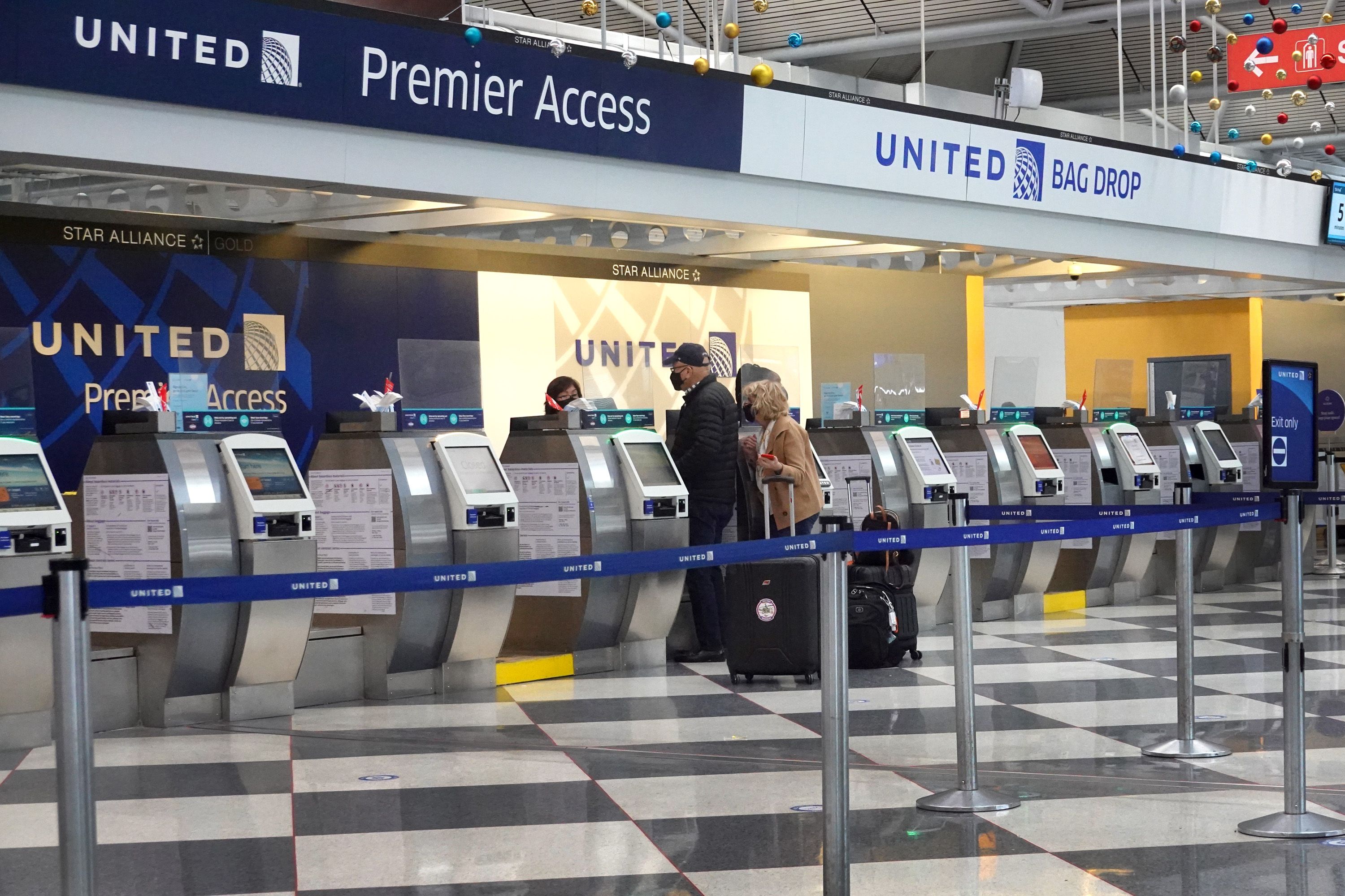 Two people stand in front of a mostly empty United airlines check in counter 
