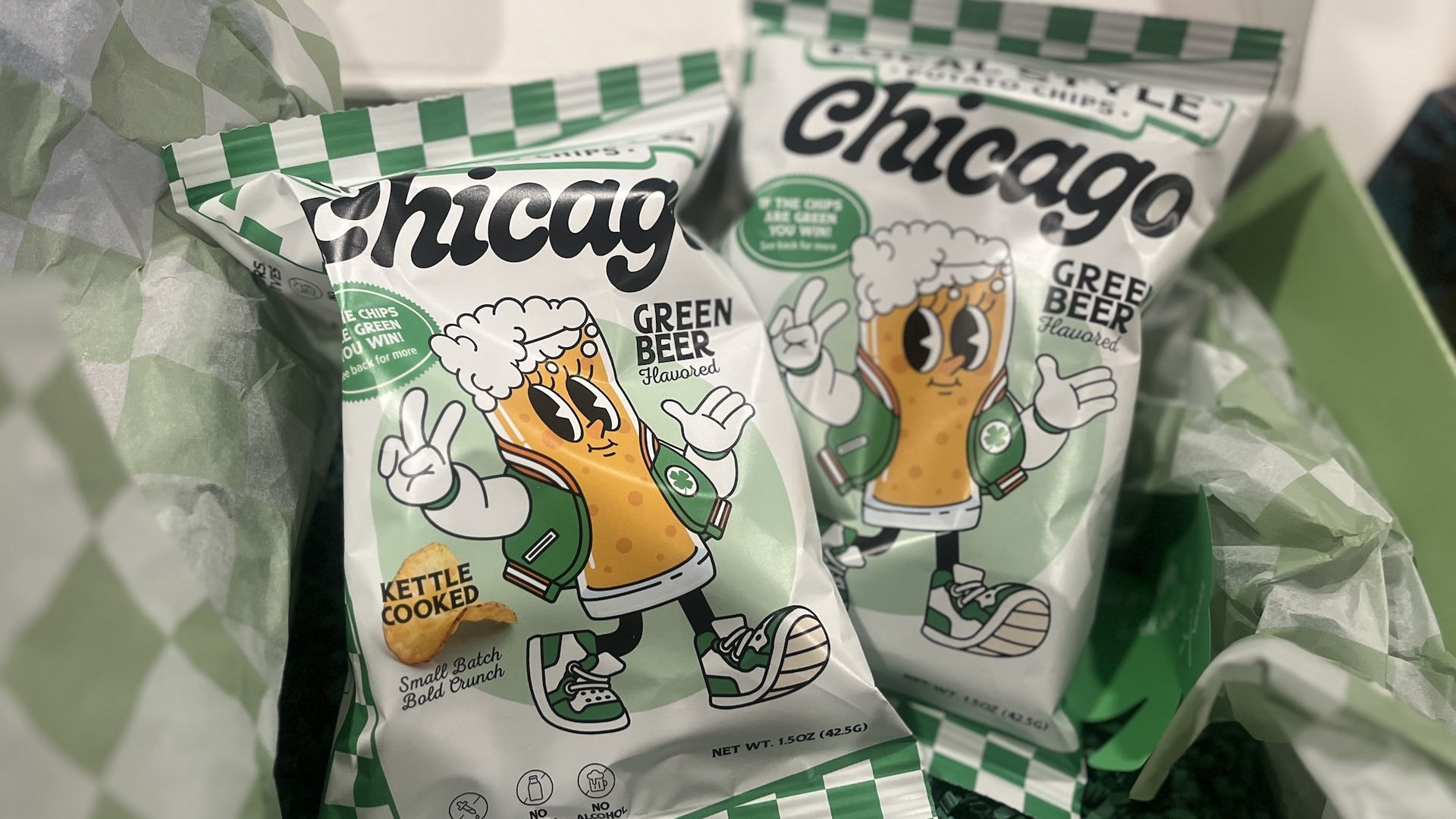 Two bags of Chicago-style kettle cooked potato chips with green beer flavor, featuring a cartoon beer character wearing a green jacket and sneakers, on white and green checkered packaging.
