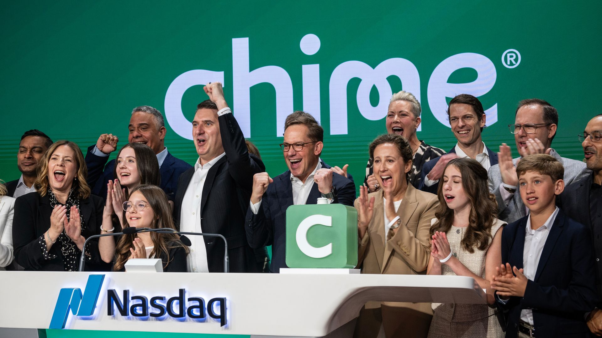 People celebrate at the Nasdaq in front of a Chime logo.