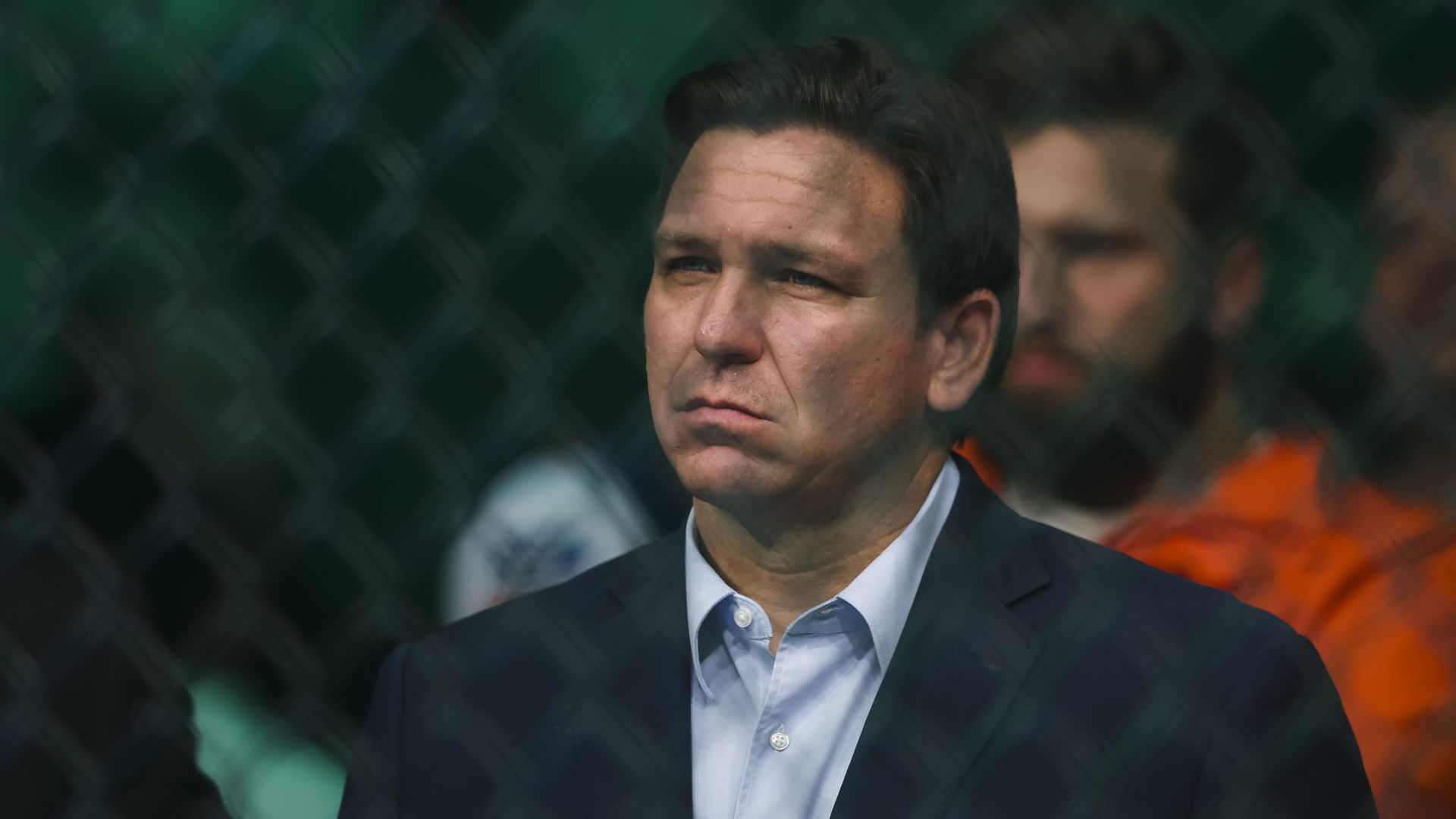 Photo of Ron DeSantis standing behind a fence