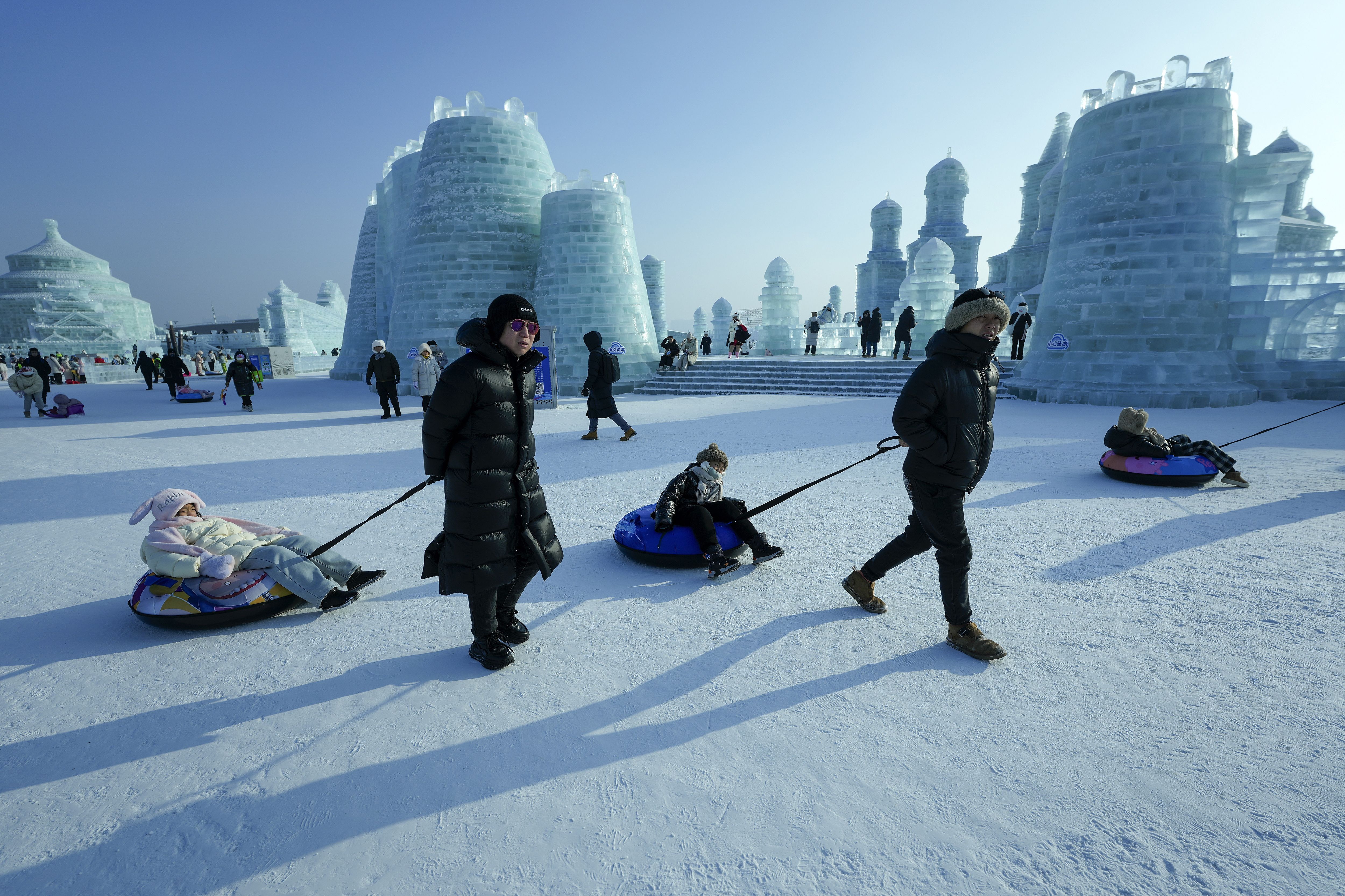 People pull their children on inflatable tubes as they visit the Harbin Ice and Snow World in Harbin, China's Heilongjiang province on Jan. 6, 2025. (AP Photo/Andy Wong)