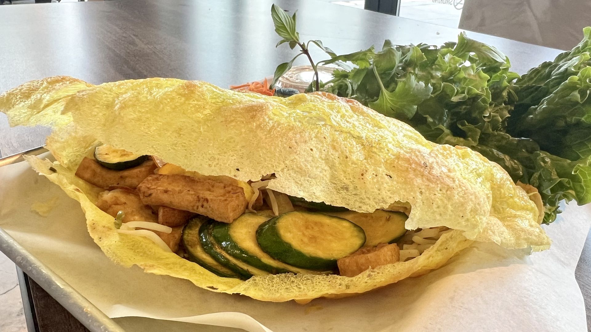 Photo of a crepe stuffed with tofu with lettuce on the side