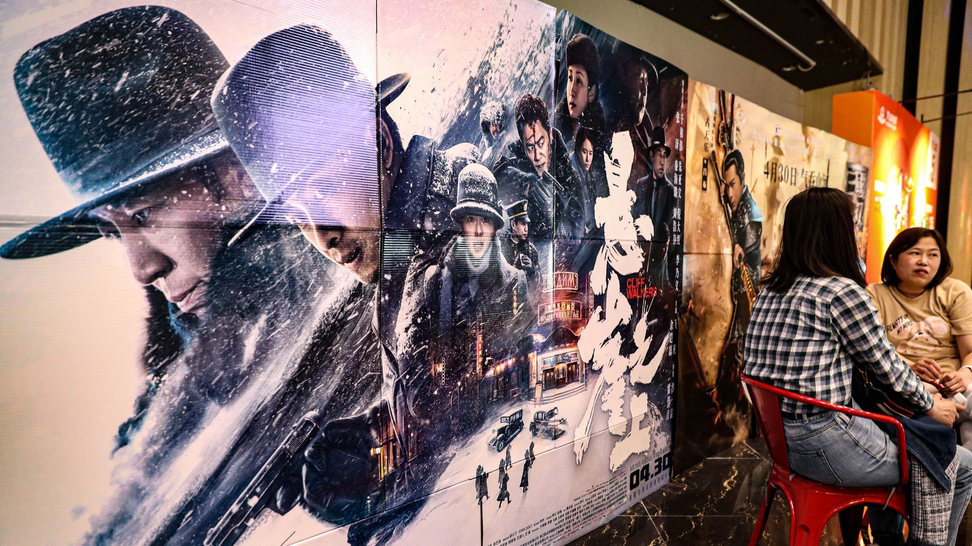 Moviegoers sit in front of a poster of film 'Cliff Walkers' at a cinema on the third day of the May Day holiday on May 3, 2021 in Shenyang, Liaoning Province of China