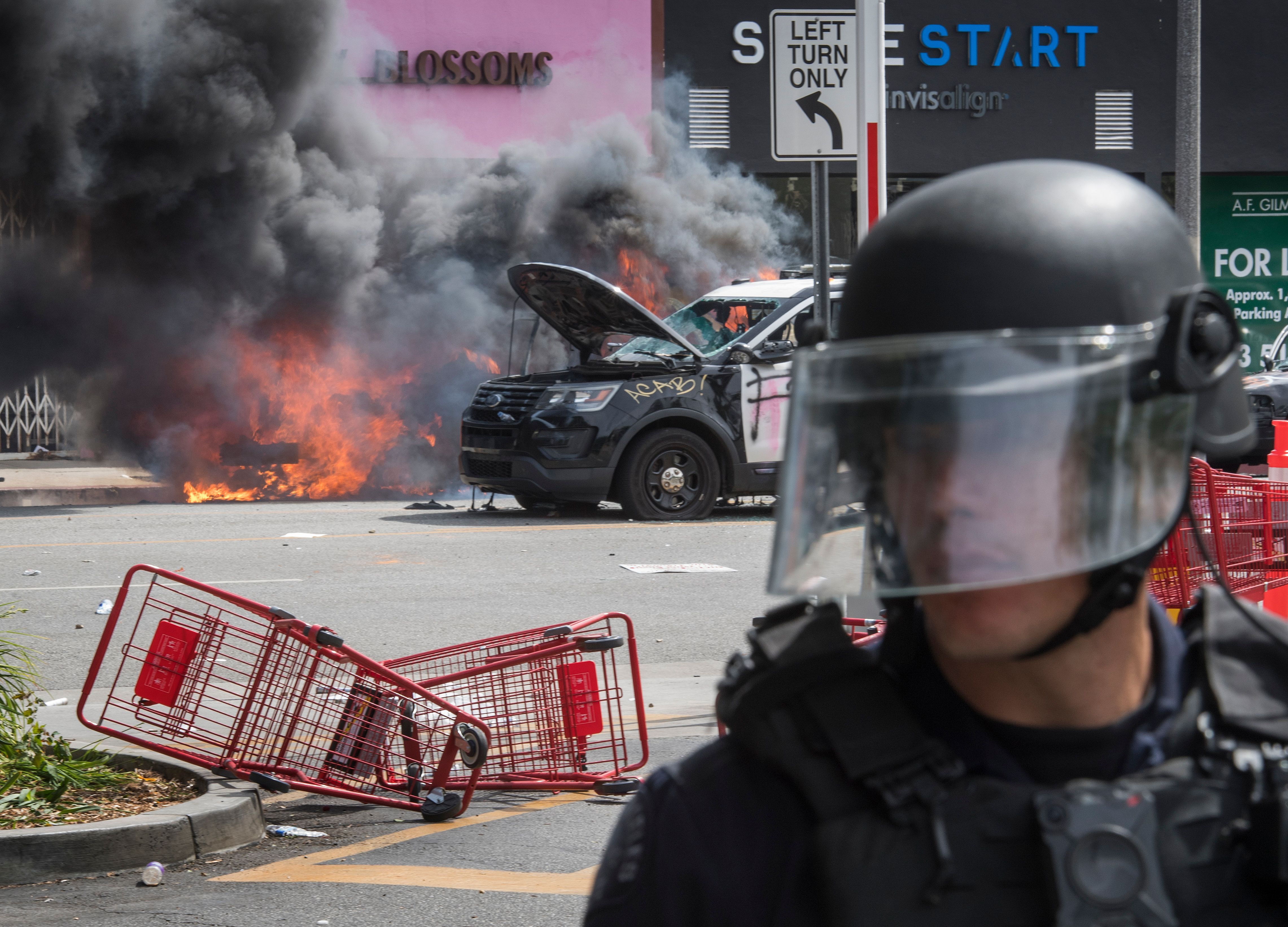 Police vehicles burn after being set on fire by demonstrators in the Fairfax District as they protest the death of George Floydon May 30, 2020 in Los Angeles.