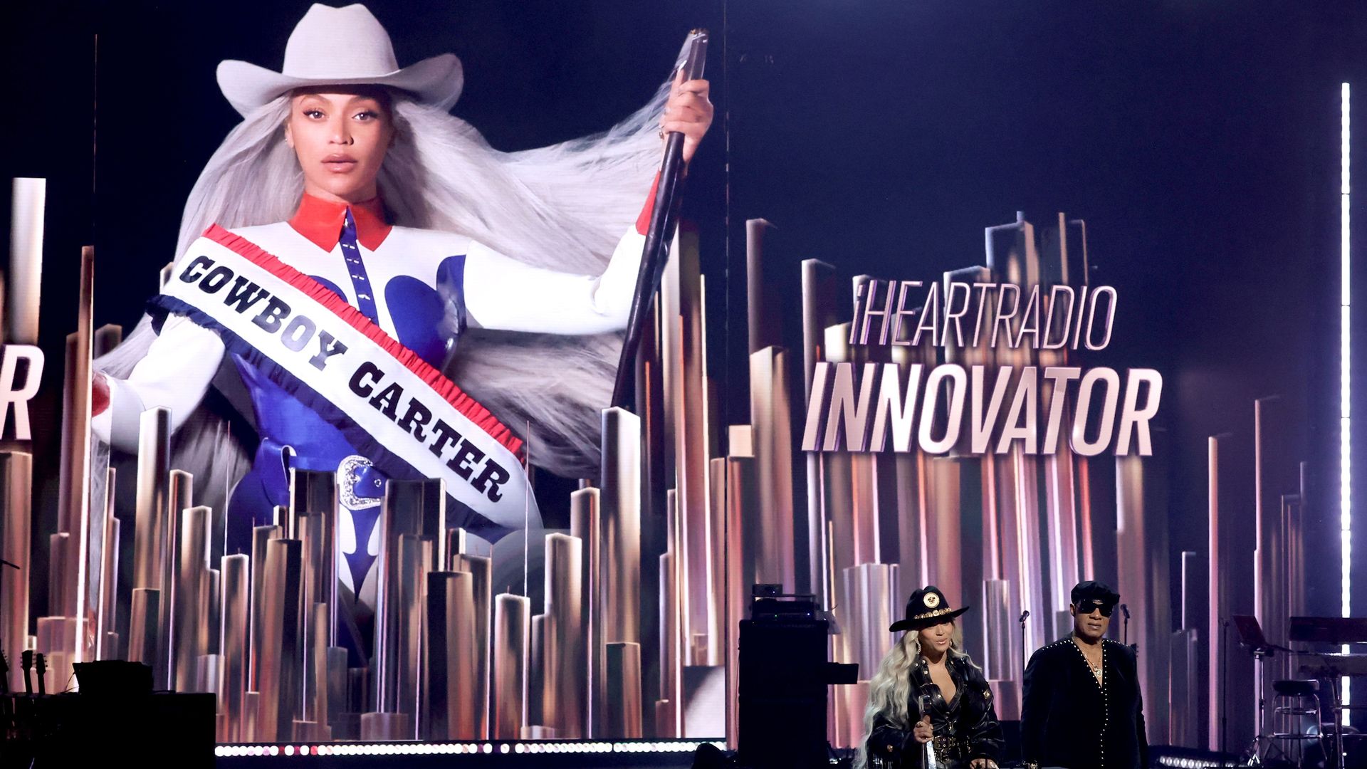A big cowboy carter album cover behind Beyonce on state with Stevie Wonder 