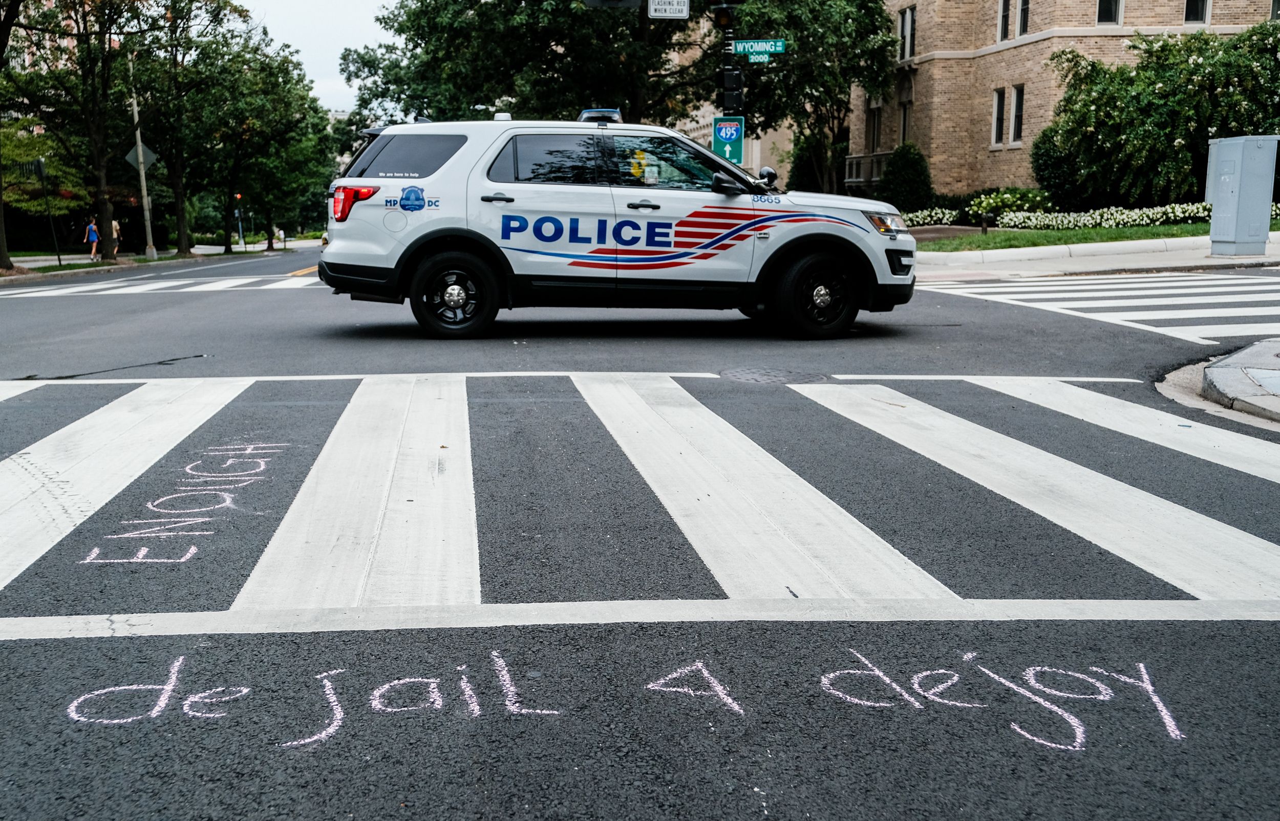 "de jail for de joy" written in chalk on a crosswalk.