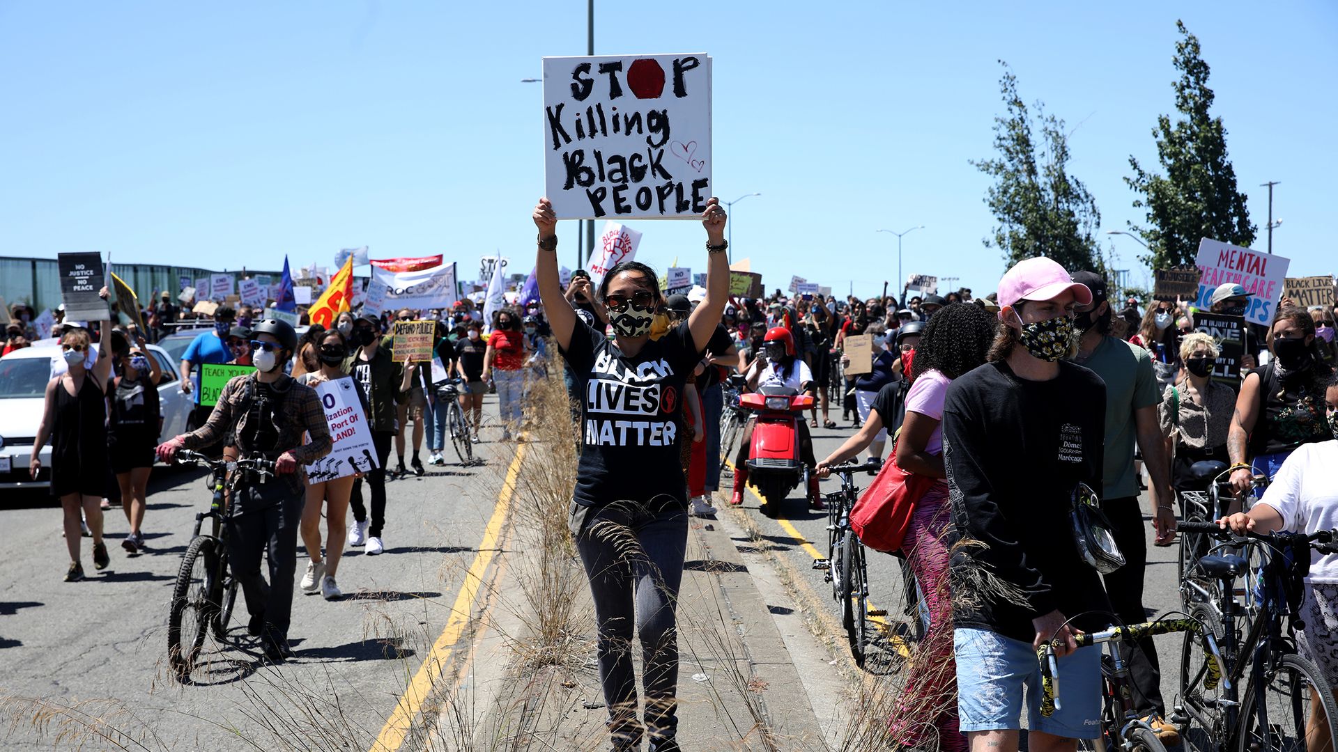 People march along Adeline St. during a Juneteenth protest as a woman holds sign that says "Stop killing black people"
