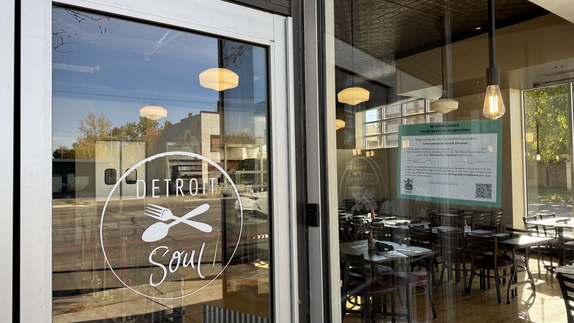 A green sign shown in the window next to the restaurant's logo.