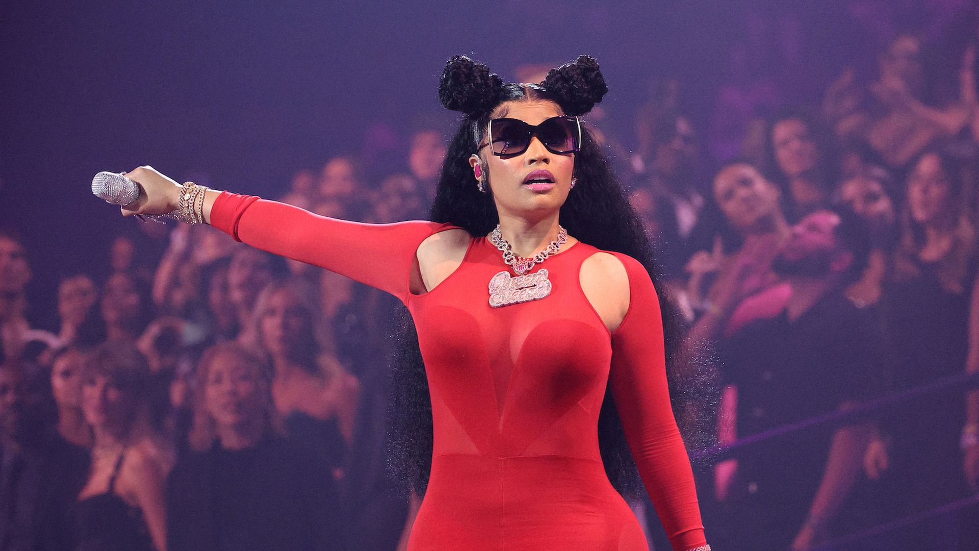 Nicki Minaj performs on stage in a red bodysuit. 