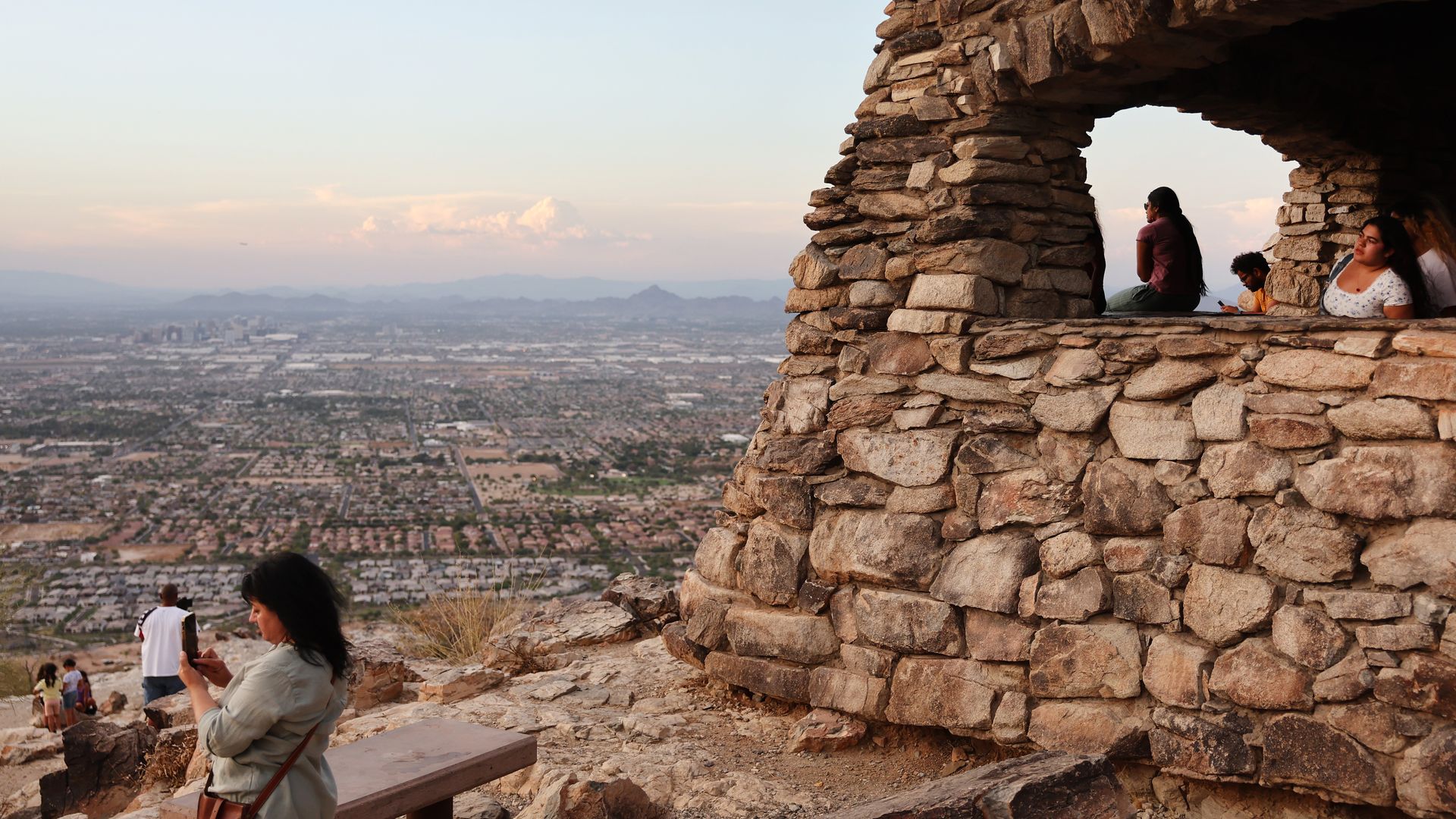 People watching the sunset in a rock structure. 