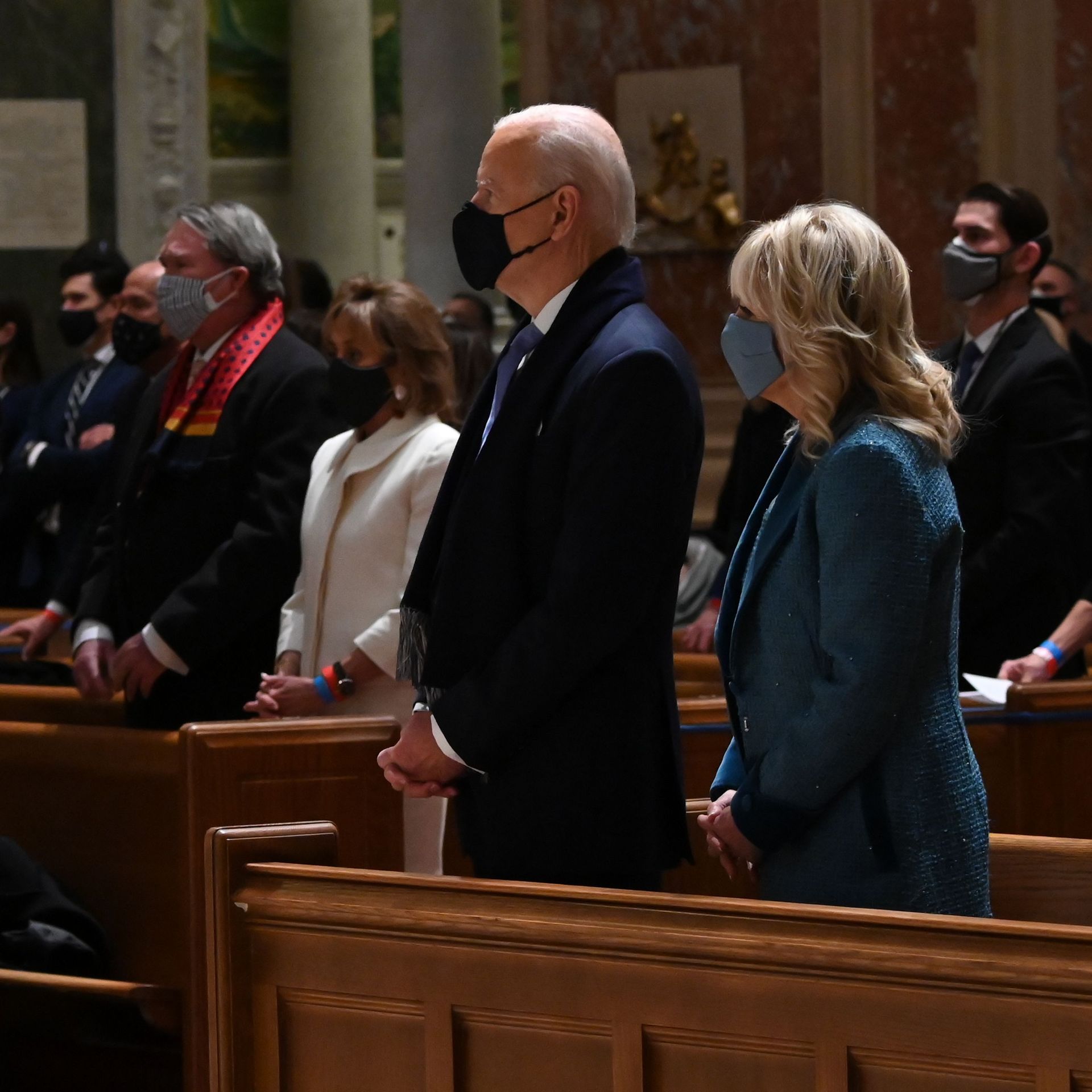 Joe Biden and Jill Biden stand next to each other in a church pew