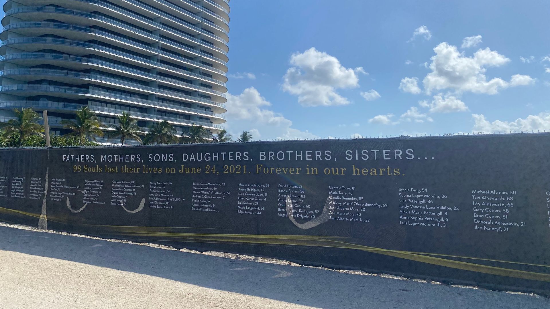 Memorial signage lines a fence blocking the site of the building collapse that left 98 dead in Surfside, Florida.