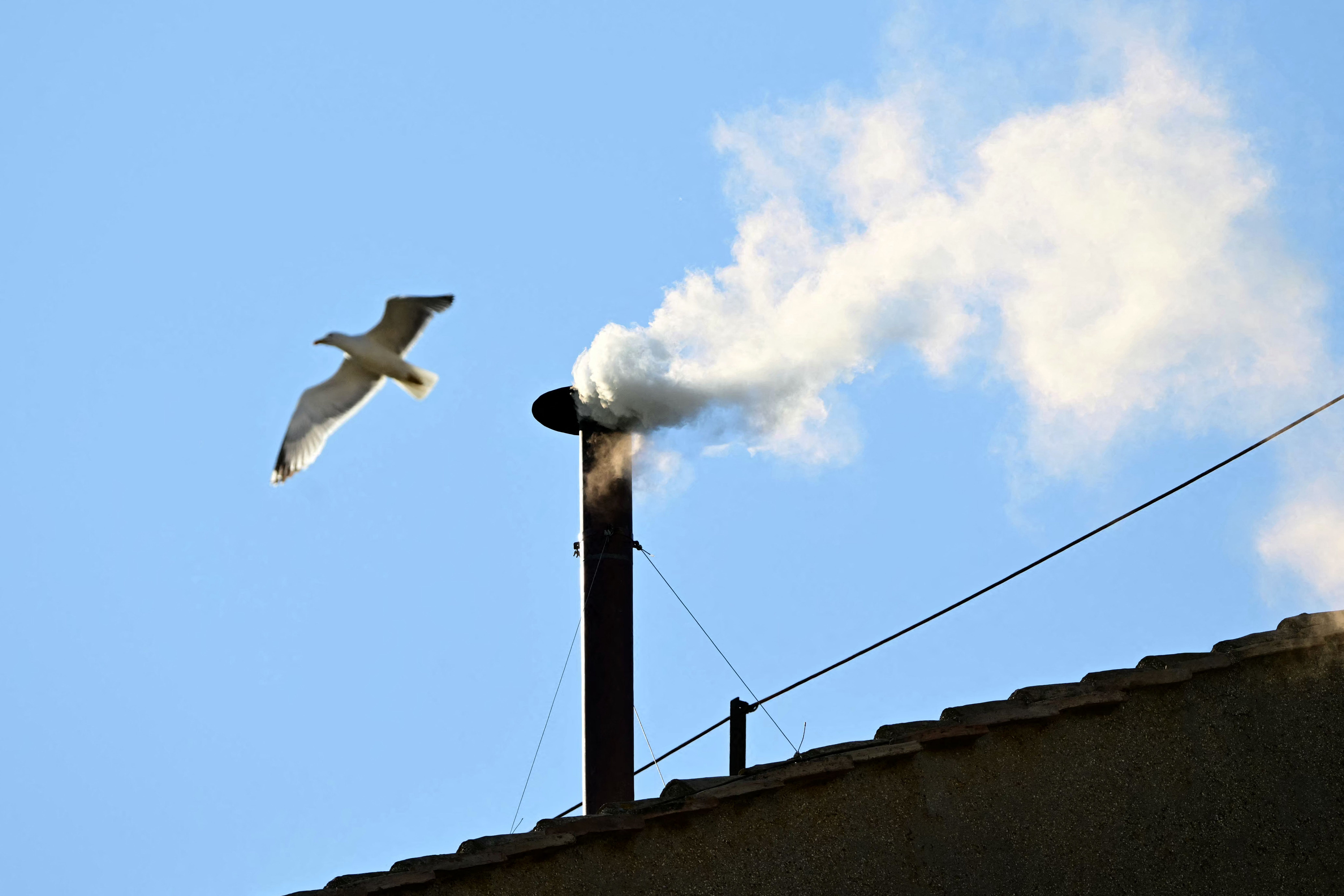 TOPSHOT - This photograph shows white smoke rising from the chinmey of the Sistine Chapel signaling that cardinals elected a new pope during their conclave in the Vatican on May 8, 2025. (Photo by Tiziana FABI / AFP) (Photo by TIZIANA FABI/AFP via Getty Images)